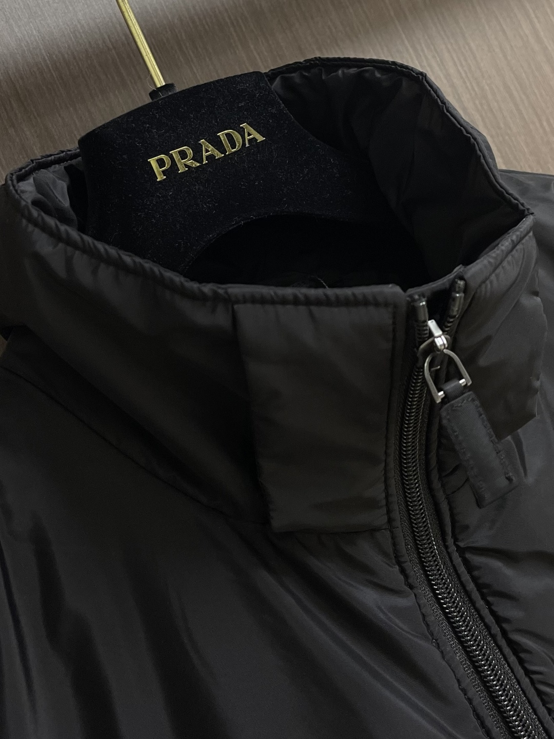 PRADA 2025FW秋冬新款连帽羽绒外套，选用品牌标志性的再生尼龙面料，与传统尼龙性能相当，具备高强