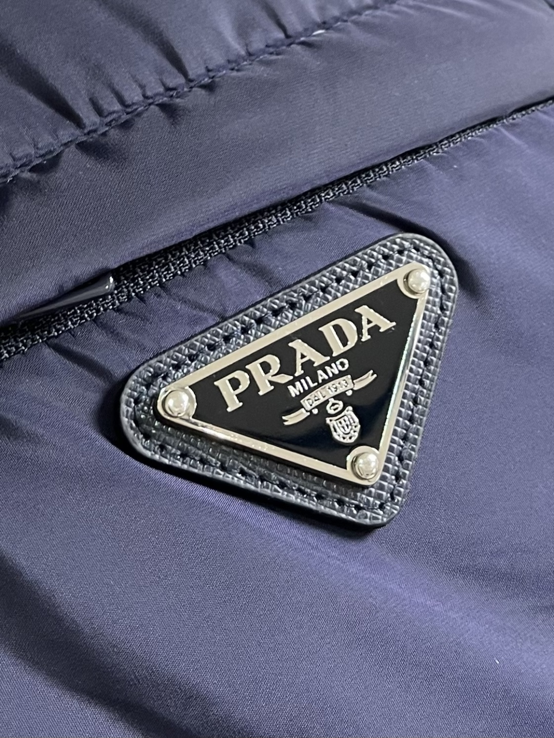 PRADA 2025FW秋冬新款连帽羽绒外套，选用品牌标志性的再生尼龙面料，与传统尼龙性能相当，具备高强