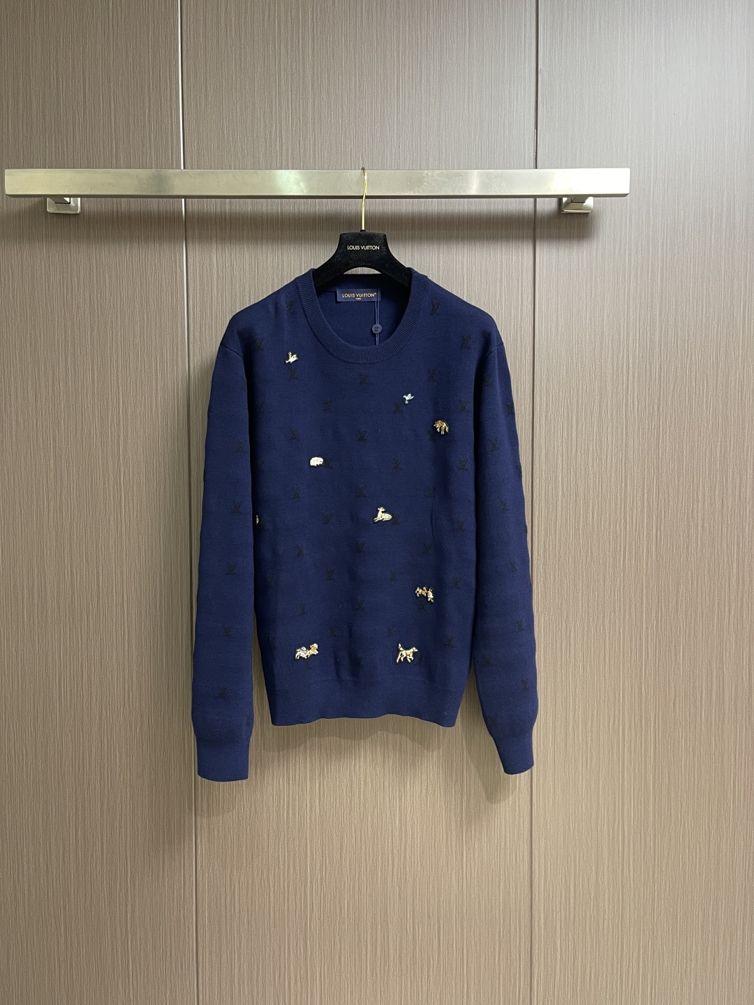 NO:661077,LV  Animal embroidered wool round-neck knitted sweater. This Louis Vuitton navy blue sweater is made of ultra-fine merino wool blended yarn and is woven through worsted knitting technology. It uses 16-needle high-density plain knitting technology to give the fabric a delicate touch like silk.  It has a matte feel and a mini Monogram pattern woven into the base of the body using dark jacquard craftsmanship of the same color. The pattern is low-key and blends naturally with the wool texture. The decorative details embellished on the body are made with hand-made beads and metal veneer inlays.  The panels are aged by electroplating and enamel color-filled, and each decoration is hand-positioned and sewn by craftsmen to ensure firmness and staggered beauty of arrangement. The round neckline adopts double-needle overlock knitting technology, which is not easy to deform and fits the neck, side seams and hem of the body.  Seamless splicing technology is used to reduce friction when wearing, and the overall stitching is even and fine, fully demonstrating the brand's exquisite craftsmanship and detail control in the field of knitted garments. The overall wiring is straight and delicate, the fabric is comfortable and soft, and the color is consistent without color difference.  It can be matched with the same style to create a fashionable look, and can be used in various occasions. Customized accessories, complete with three standards, same style for men and women!  Size S-XL S size bust 108 shoulder width 47 length 66 M size bust 112 shoulder width 49 length 68 L size bust 116 shoulder width 51 length 70 XL size bust 120 shoulder width 53 length 7219860909LV 动物刺绣羊毛圆领针织毛衣,这款路易威登藏青色针织衫选用超细美利奴羊毛混纺纱线,经精纺针织工艺织就,采用16针高密平纹针织技法,让面料呈现出如丝绸般的细腻触感与哑光质感,衣身基底还以同色系暗纹提花工艺织入迷你Monogram图案,花纹低调且与羊毛纹理自然融合.衣身点缀的装饰细节采用手工钉珠与金属饰片镶嵌工艺,饰片经电镀做旧与珐琅填色处理,每一处装饰均由工匠手工定位缝制,确保牢固度与排布的错落美感.圆领领口采用双针锁边针织工艺,不易变形且贴合颈部,衣身侧缝与下摆运用无缝拼接技术,减少穿着时的摩擦感,整体车工针脚均匀细密,充分展现了品牌在针织成衣领域的精湛工艺与细节把控.整体走线平直细腻,面料舒适柔软,颜色一致无色差 能与同款搭配营造时尚造型,驾驭各种场合,定制辅料,三标齐全,男女同款！尺码S-XL S码胸围108肩宽47 衣长66 M码胸围112肩宽49 衣长68 L码 胸围116肩宽51 衣长70 XL码胸围120 肩宽53 衣长72,,louis vuitton,louis vuitton,sweaters, ,Men's clothing