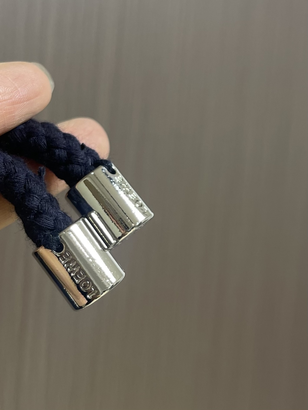 Loewe 皮标连帽长款大衣，以深邃的藏蓝为主色调，帽檐外侧中央镶嵌一枚哑光黑Logo皮标，优雅大气。人