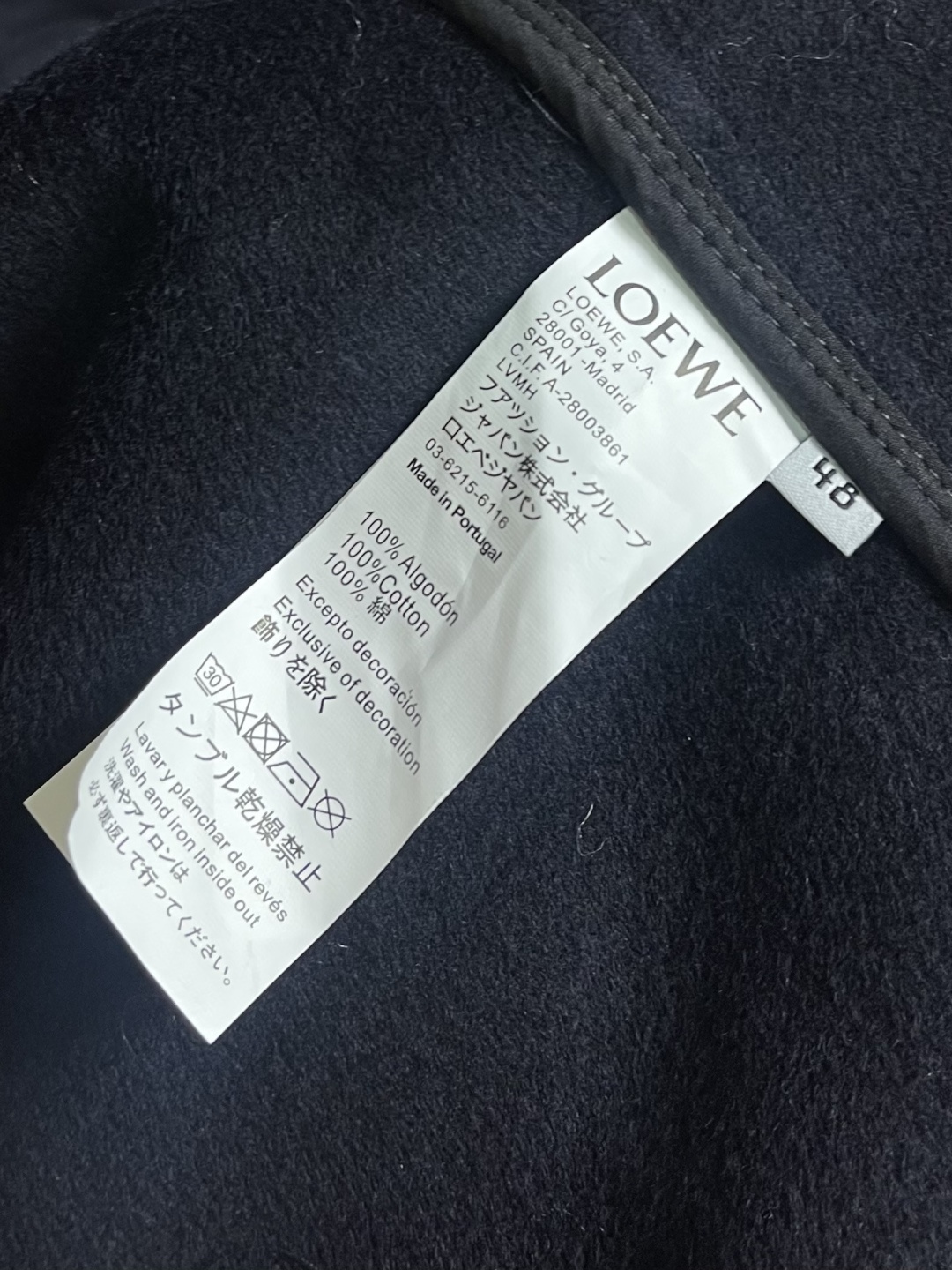 Loewe 皮标连帽长款大衣，以深邃的藏蓝为主色调，帽檐外侧中央镶嵌一枚哑光黑Logo皮标，优雅大气。人