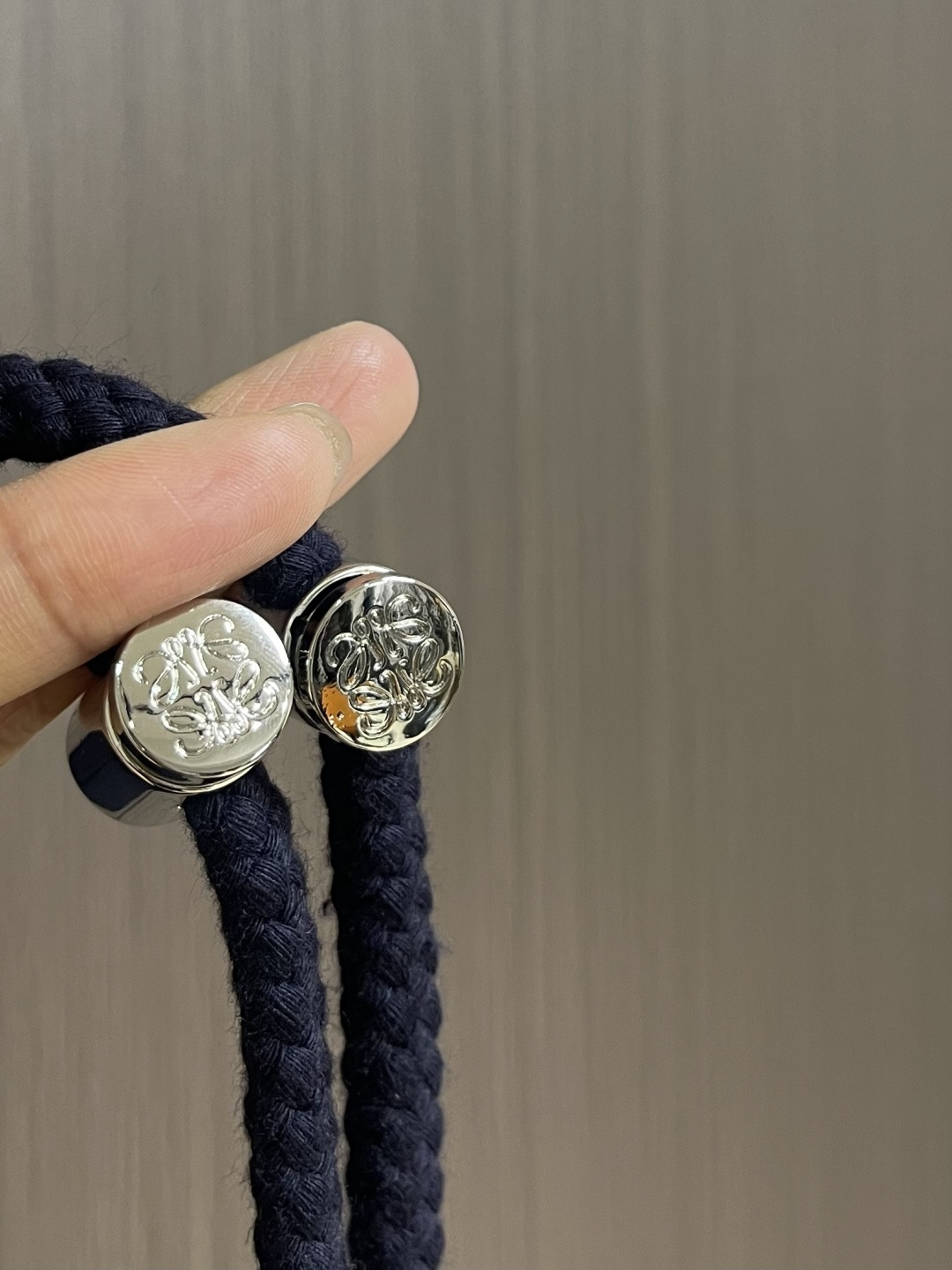 Loewe 皮标连帽长款大衣，以深邃的藏蓝为主色调，帽檐外侧中央镶嵌一枚哑光黑Logo皮标，优雅大气。人