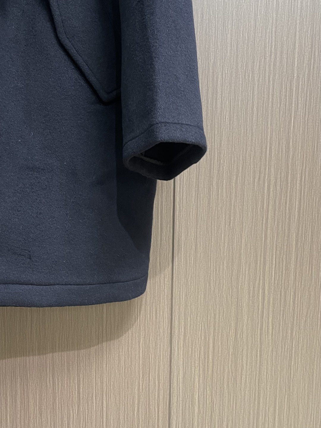 Loewe 皮标连帽长款大衣，以深邃的藏蓝为主色调，帽檐外侧中央镶嵌一枚哑光黑Logo皮标，优雅大气。人