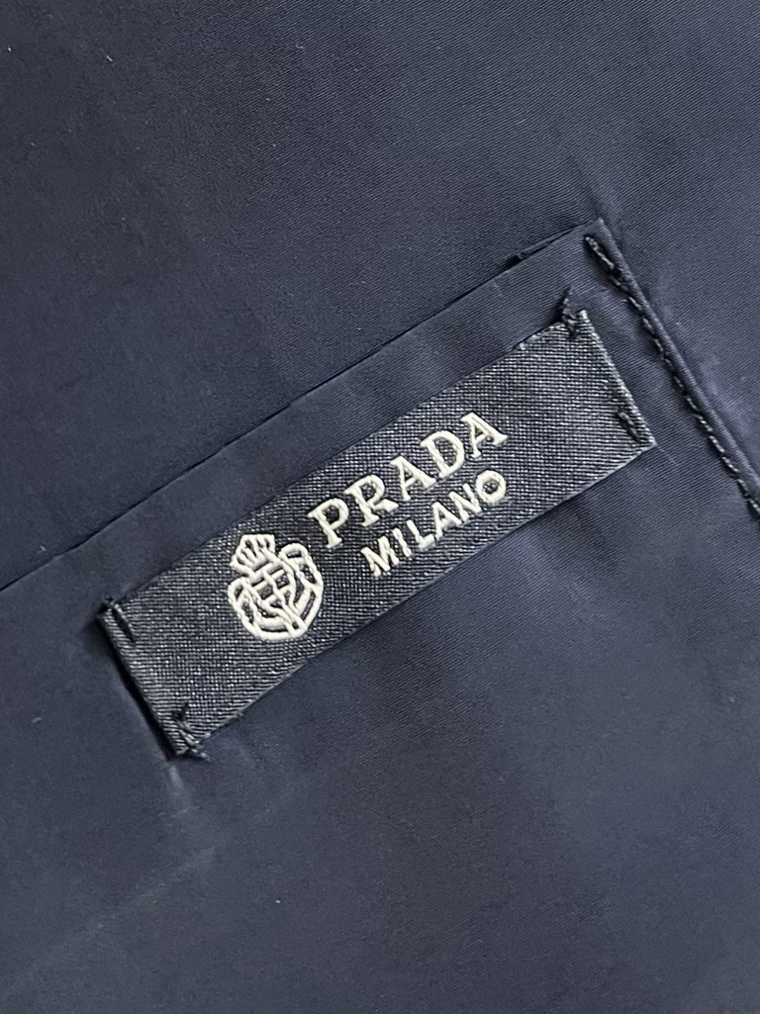 Prada 再生尼龙衬衫，Re-Nylon赋予这款经典剪裁衬衫技术风格，混搭设计融合裁缝优雅与功能性。圆