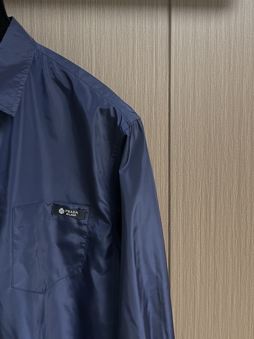 Prada 再生尼龙衬衫，Re-Nylon赋予这款经典剪裁衬衫技术风格，混搭设计融合裁缝优雅与功能性。圆