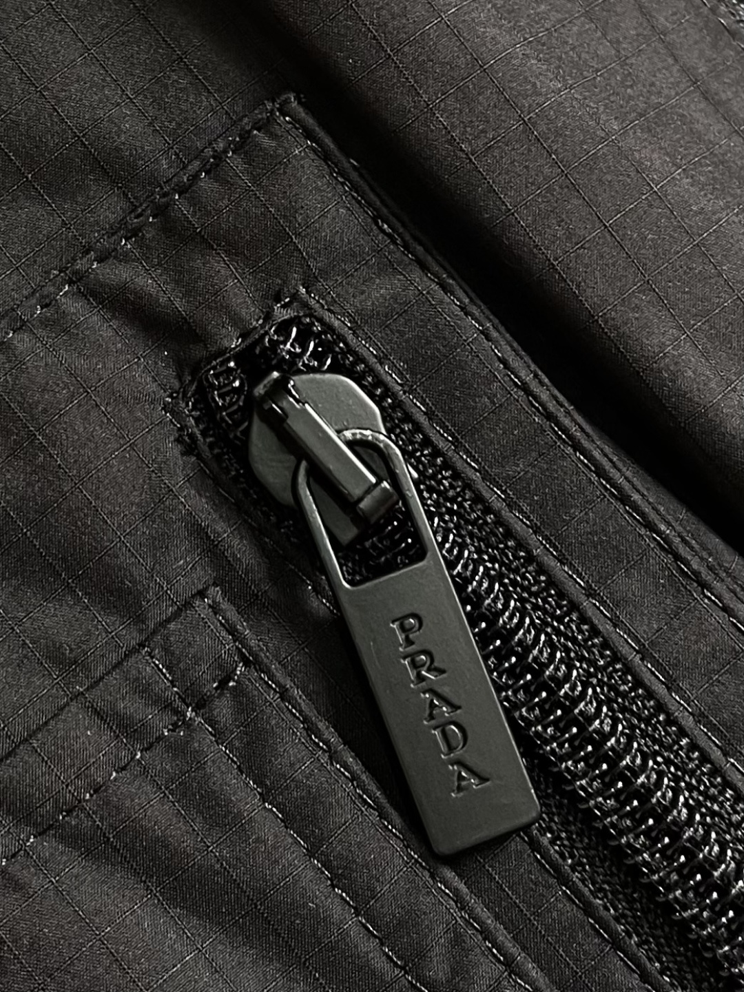 PRADA 三角标工装风秀款羽绒马甲外套，标志性的三角形徽标重释为经典图案，化身此款Re-Nylon再生