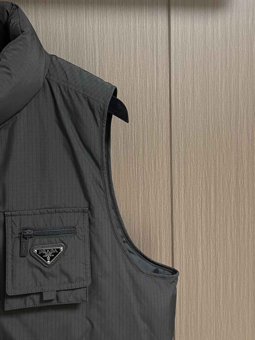 PRADA 三角标工装风秀款羽绒马甲外套，标志性的三角形徽标重释为经典图案，化身此款Re-Nylon再生