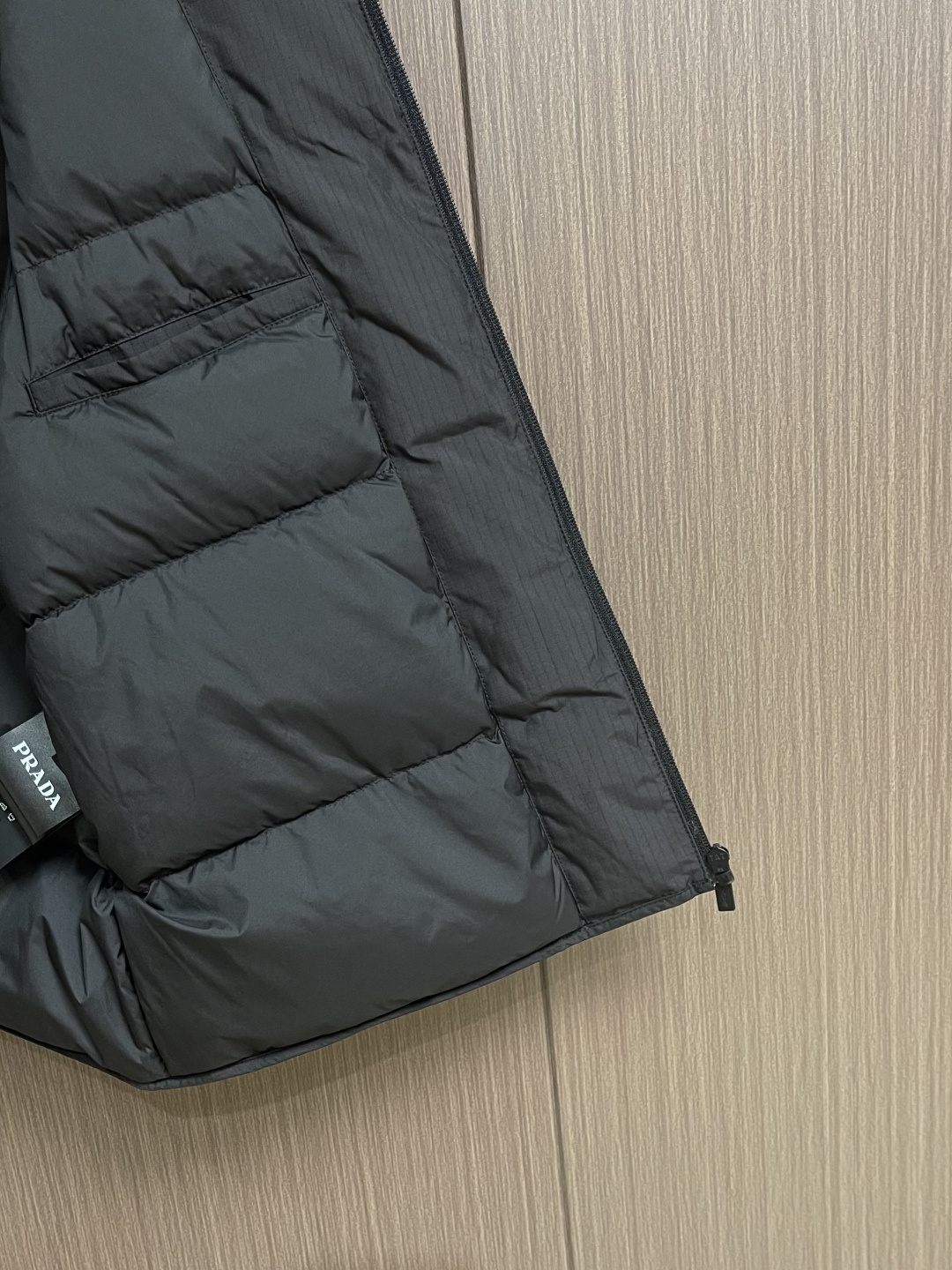 PRADA 三角标工装风秀款羽绒马甲外套，标志性的三角形徽标重释为经典图案，化身此款Re-Nylon再生