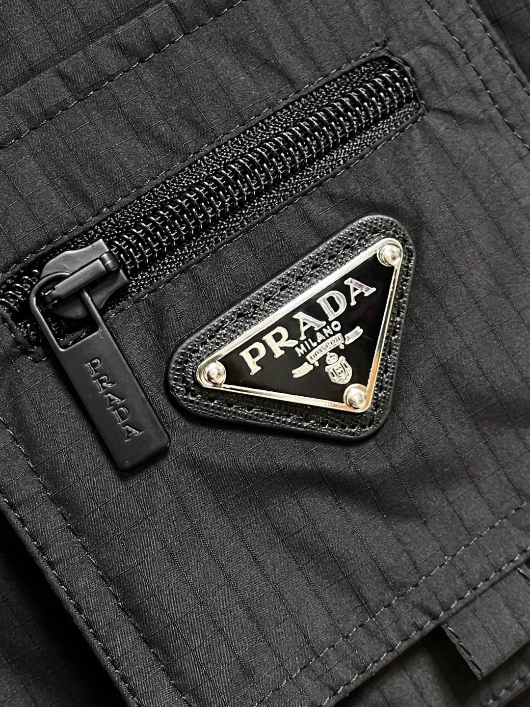 PRADA 三角标工装风秀款羽绒马甲外套，标志性的三角形徽标重释为经典图案，化身此款Re-Nylon再生