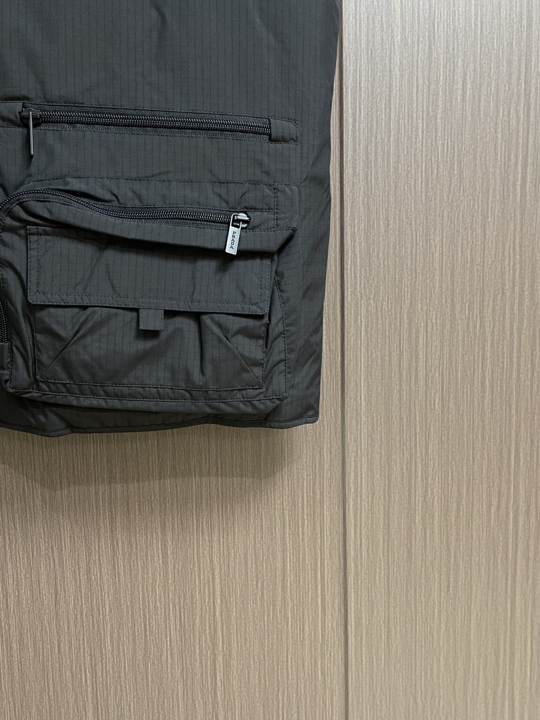 PRADA 三角标工装风秀款羽绒马甲外套，标志性的三角形徽标重释为经典图案，化身此款Re-Nylon再生