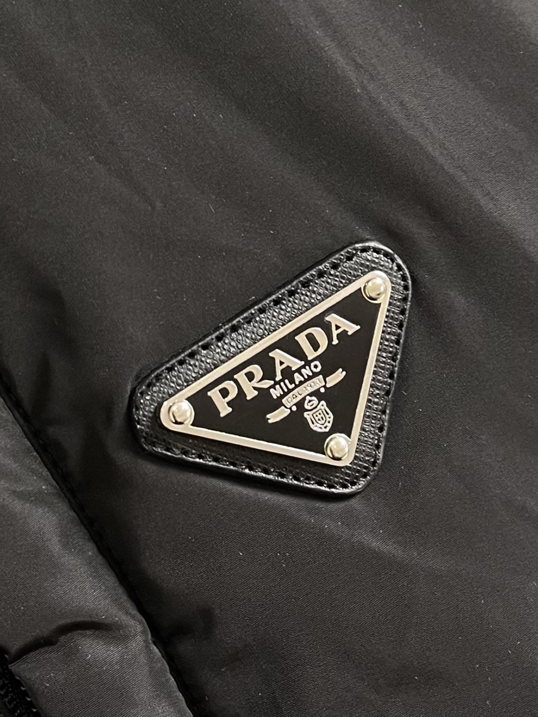 Prada Re-Nylon限定款连帽羽绒服夹克外套，这款再生尼龙羽绒饰有三角形金属徽标等精美细节，并融