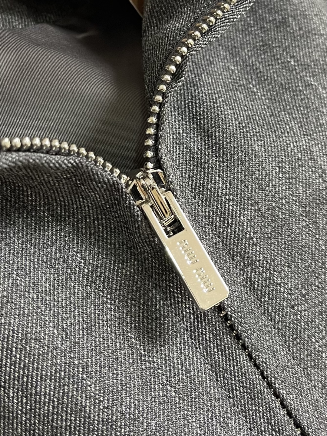 MIUMIU 立领细条纹拉链夹克外套，这款灰色细条纹夹克采用精梳羊毛混纺面料，经高温定型处理，具有良好的