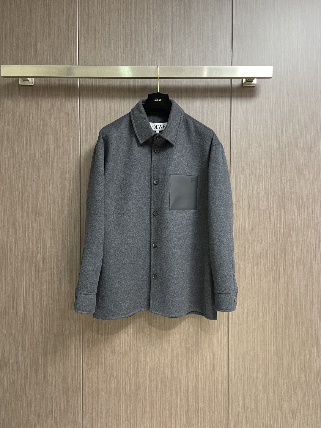 NO:730637,Support after-sales service LOEWE  Shirt-style woolen jacket, the fabric is a double-faced woolen jacket with both warmth and breathability. The wool fibers are screened to retain only fine wool with uniform length and excellent toughness, giving the fabric a crisp silhouette and natural wrinkle resistance; improving the overall touch, the suede is as fine as clouds, achieving a 'light and warm' wearing experience. Special textile techniques are used to interweave wool and cashmere fibers to form a subtle two-color texture, which eliminates the need for linings.  The fabric structure is precisely controlled at about 280g per square meter to ensure that it does not appear bulky when worn alone, and can withstand the cool weather when worn alone. The process adopts the traditional double-sided sewing process and is operated by more than experienced seamstresses. There are no exposed stitches on the body of the garment, and the two layers of fabrics are accurately fitted through blind stitching techniques. The stitch density is controlled at 3-4 stitches per centimeter to ensure that the edges are smooth and compliant while retaining the natural drape of the fabric.  It not only improves the durability, but also gives the jacket a minimalist and high-end look visually. The leather patch pocket on the chest is made of vegetable-tanned calfskin, which is dyed with vegetable tannins to give a matte black deep texture. The leather is precisely cut into a square shape with uniform specifications, and then hand-positioned and sewn to the body to ensure the tension balance with the wool fabric and avoid deformation after long-term wear. The Anagram embossing on the bag uses a 0.3mm depth steel mold hot pressing process.  A clear three-dimensional brand logo is formed on the leather surface, and each edge of the pattern has been calibrated repeatedly to ensure smooth lines and low-key recognition. Behind the regular version is millimeter-level size control, and the collar angle is set to 85°, which not only retains the crispness of the shirt but also avoids neck jamming; the shoulder width is 2cm longer than the standard version, taking into account comfort and a lazy and casual atmosphere. Sizes 46-52, loewe, jackets  & coats,jackets & coats,shirts,cowhide,19860909支持年后售后 LOEWE 衬衫式羊毛呢夹克外套,面料选择兼具温度与呼吸感的双面呢外套.羊毛纤维经筛选仅保留长度均匀、韧性卓越的细支羊毛,赋予面料挺括廓形与天然抗皱性；提升整体触感,绒面细腻如云朵,实现「轻盈保暖」的穿着体验.通过特殊纺织技法使羊毛与羊绒纤维交织融合,形成正反双色的微妙肌理,既省去内衬的束缚,又让衣身更显利落.这种面料结构,每平方米克重精准控制在280g左右,确保叠穿不显臃肿,单穿亦能抵御微凉气候.工艺采用传统双面呢缝制工艺,由经验超过缝纫师操作.衣身无外露缝线,通过暗缝技法将两层面料精准贴合,针脚密度控制在每厘米3-4针,确保边缘平整服帖,同时保留面料自然的垂坠感.不仅提升耐穿度,更让外套在视觉上呈现极简高级感.胸前皮革贴袋选用植鞣小牛皮,经植物单宁浸染后呈现哑光黑的深质感.皮革精准裁剪统一规格的方正形态,再通过手工定位缝制于衣身,确保与羊毛面料的张力平衡,避免长期穿着后变形.袋面的Anagram压纹采用0.3mm深度的钢模热压工艺,在皮革表面形成清晰立体的品牌标识,每一个处图案边缘都经过反复校准,确保线条流畅,低调中体现辨识度.常规版型的背后是毫米级的尺寸把控衣领角度设定为85°,既保留衬衫式的利落,又避免卡颈；肩宽比标准版型增加2cm,兼顾舒适度与慵懒随性的氛围.尺码46-52,,loewe,jackets & coats,jackets & coats,shirts,cowhide,,Men's clothing