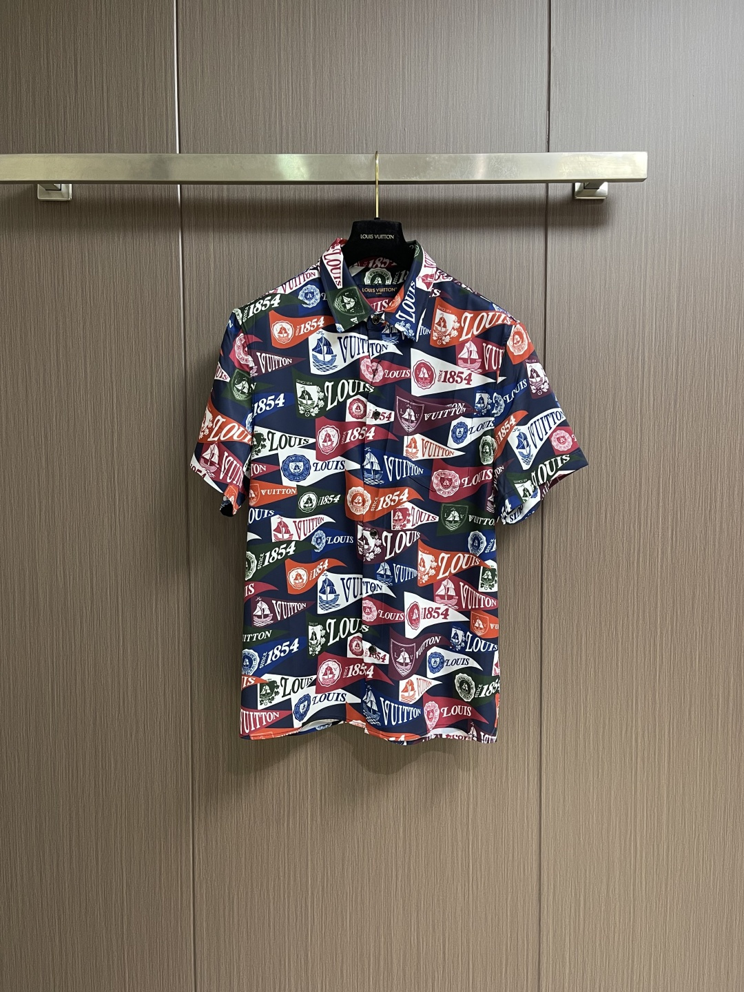 NO:756932,Tops shorts LV  Logo-printed all-over lapel short-sleeved shirt and shorts suit, made of 55% viscose fiber and 45% mulberry silk blended fabric, which combines the luxurious luster of mulberry silk and the drape and stiffness of viscose fiber. It feels as delicate and silky as clouds, skin-friendly, breathable and has a cool feeling, perfect for spring and summer light wearing needs; the body is fully printed with classic LV flags and 4 commemorative elements, retro nautical patterns are interlaced, and the colors are rich and layered, easily creating a rich atmosphere.  It has a rich college vacation atmosphere with high visual recognition; the classic pointed collar design fits the neck line, and the placket is equipped with customized brand buttons, opening and closing smoothly and with exquisite texture; the overall use of loose short-sleeved silhouette, the tailoring is casual and not tight, and it is tolerant and can be controlled by all body shapes; the garment process uses high-precision digital printing technology to ensure that the pattern is not easy to fade and crack after long-term washing, the stitching is fine and neat, and the seams at the splicing are smooth and firm. Sizes S-XL  46-52,,louis vuitton,shorts,shirts,T-shirt,19860909上衣 短裤 LV 徽标满印翻领短袖衬衫短裤套装,采用55％粘胶纤维与45％桑蚕丝混纺面料,集桑蚕丝的奢润光泽与粘胶纤维的垂坠挺括于一身,触感如云朵般细腻丝滑,亲肤透气且自带凉感,完美适配春夏轻盈穿着需求；衣身满印经典LV旗帜与4纪念元素,复古航海纹样交错排布,色彩浓郁层次分明,轻松营造浓郁的学院度假氛围,视觉辨识度极高；经典尖领设计贴合颈部线条,门襟搭配定制品牌纽扣,开合顺滑且质感精致；整体采用宽松短袖廓形,剪裁随性不紧绷,包容性强各类身形皆能驾驭；成衣工艺上采用高精度数码印花技术,保证图案久洗不易褪色开裂,针脚细密工整,拼接处锁边平整牢固.尺码S-XL 46-52,,louis vuitton,shorts,shirts,T-shirt,,Men's clothing