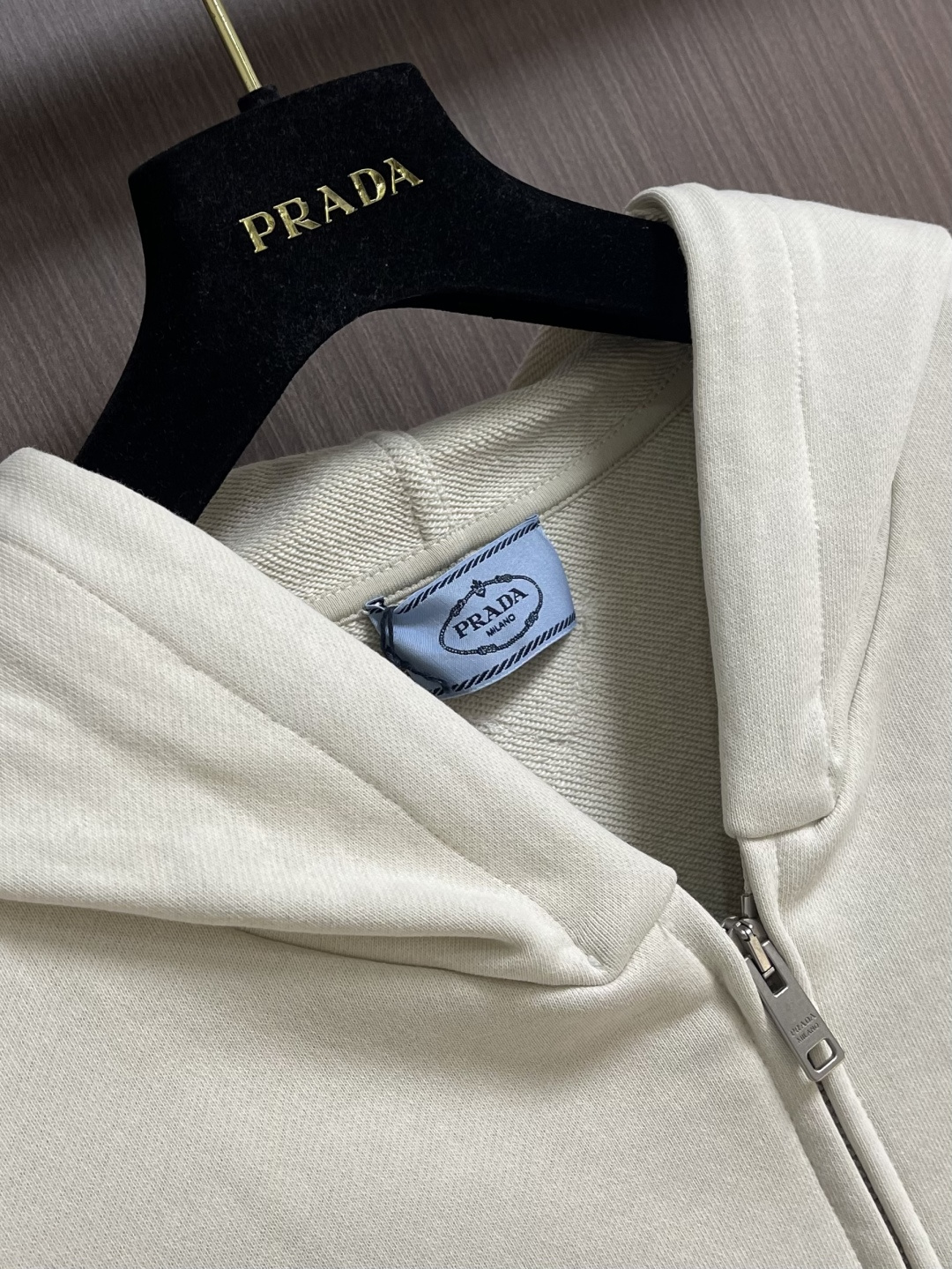 Prada 学院拉链连帽外套，采用32支单纱面＋16支纱底的卫衣面料结构，克重为320gm2；搭配的21