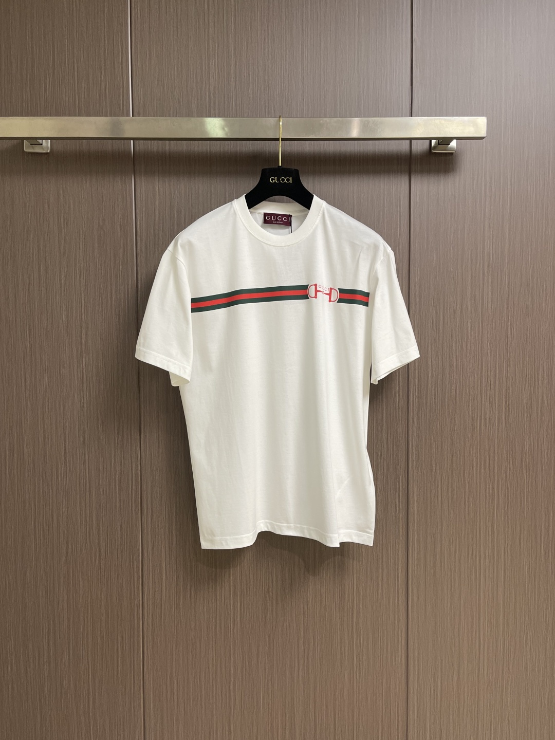 NO:756900,Gucci web lock round neck short-sleeved T-shirt, specific mercerized long-staple cotton fabric, made of 50S double-strand mercerized cotton, weight 165gm2; matched with 32S  1x1 tensioner thread, 300gm2. The high count of the fabric ensures that the yarn is extremely fine, giving the fabric a silky and delicate touch; double-twisting greatly improves the yarn strength and pilling resistance, solving the shortcomings of high-count yarns that are easy to be fragile; the fabrics made are usually softer, smoother and finer. Mercerization. The cotton fiber is permanently glossed through alkali solution, making the fabric appear silk-like.  luster, while enhancing fiber strength, dye adsorption and dimensional stability. Webbing lock glue printing, environmentally friendly elastic glue suede printing is a composite process that combines elastic coating and velvety texture. It first transfers the environmentally friendly elastic glue to the fabric through a high mesh screen to form a flexible base with excellent stretchability; special velvet powder is implanted on the surface of the incompletely cured glue layer for velvet pressing  After precise temperature control and curing, a decorative layer integrating matte suede texture and elastic coating is formed. The pattern area has the stretch-resistant and anti-cracking properties of elastic glue and the delicate touch and matte vision of suede. The touch is soft and plump without hardening. The suede texture can be accurately presented with the printing shape, the color is saturated and full of three-dimensional layers, and it has both decorative beauty and wearing comfort. Simple  Approximately vertical round neck short-sleeved version, standard straight cut creates a simple and modern silhouette through the three-dimensional shoulder line and vertical body proportions. The back collar adopts triple anti-deformation technology with built-in memory inserts, ultrasonic fit interlining and double-needle four-thread reinforced sewing. The hem and cuffs are edged with special-purpose machine-made open stitching, and the seam tension is precisely calibrated to ensure that it remains flat after multiple washes. Sizes XS-L  XS size, shoulder width 48, chest size 106, length 69, size S, size shoulder width 49.5 size, chest size 110, length 71 size M, size shoulder width 51, size chest 114 size, length 73 size L, size shoulder width 52.5, chest size 118 size, length 75, gucci, T-shirt, tees, t-shirt, real silk,19860909Gucci 织带锁扣圆领短袖T恤,特定丝光长绒棉面料,采用50S双股丝光棉,克重165gm2；搭配32S 1x1拉架螺纹,300gm2.面料高支数确保纱线极细,赋予织物丝绸般的细腻触感；双股捻合则大幅提升纱线强度与抗起球性,解决了高支纱易脆弱的缺点；制成的面料通常越柔软、光滑且精细.丝光处理.通过碱液对棉纤维进行永久性光泽整理,使面料呈现真丝样光泽,同时增强纤维强度、染料吸附力与尺寸稳定性.织带锁扣胶浆印花,环保弹力胶浆绒面印花是一种结合弹性涂层与绒感肌理的复合工艺.其先通过高目数网版将环保弹力胶浆转印至面料,形成具备优异拉伸性的柔韧基底；在未完全固化的胶浆层表面植入特制绒粉进行压绒处理,经精准控温固化后,形成哑光绒面质感与弹性涂层一体化的装饰层.图案区域同时具备弹力胶浆的耐拉伸、抗开裂特性与绒面的细腻触感和哑光视觉,触感柔软丰盈无硬化感.绒面纹理可随印花形状精确呈现,色彩饱和且富有立体层次,兼具装饰美观与穿着舒适度.简约垂直圆领短袖版型,标准直筒剪裁通过立体肩线与垂直衣身比例,营造简约现代轮廓.后领采用三重防变形工艺内置记忆嵌条、超声波贴合衬布与双针四线加固缝制.下摆及袖口以专机坎车明线收边,缝线张力经过精密校准,确保多次洗涤后仍保持平整形态.尺码XS-L XS码肩宽48 胸围106 衣长69  S码肩宽49.5 胸围110衣长71  M码 肩宽51胸围114衣长73 L码 肩宽52.5胸围118衣长75,,gucci,T-shirt,tees，t-shirt,real silk,,Men's clothing