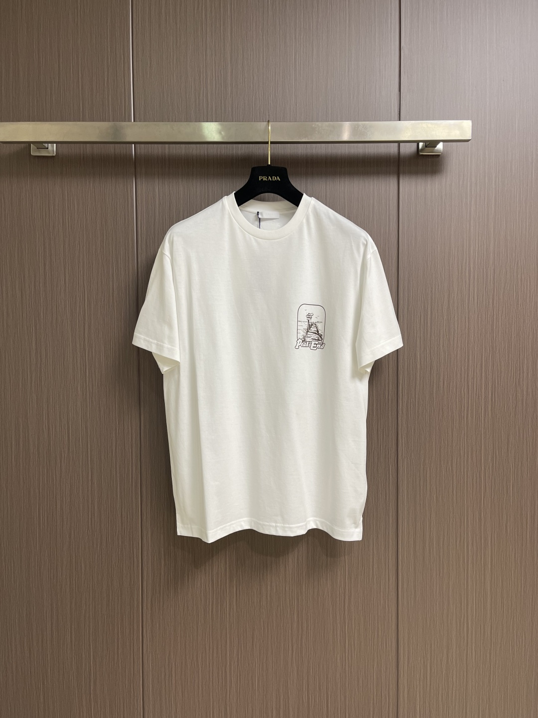 NO:745927,Prada  The boat port printed round neck short-sleeved T-shirt is made of 50-count double-strand mercerized cotton with a weight of 165gm2; it is paired with a 32-count double-yarn high-weight 300gm2 ribbed collar, which provides solid and reliable elastic support for the light and thin body. The 50-count double-strand fabric means  The yarn is extremely fine and plied and reinforced, giving the fabric a silky, silky feel and excellent anti-pilling durability. The mercerizing treatment brings a permanent soft luster and stronger color expression. The weight of the fabric is light to medium, ensuring T  The shirt is extremely light, breathable and has a smart drape. The ship port printing pattern is processed with silicone oil + environmentally friendly dot slurry printing process, using environmentally friendly water-based slurry, and printed in the form of tiny dots through high-precision screens. Its function is to achieve delicate transitions and layers of colors, maintain the breathability and soft touch of the printed area, and avoid the hardening of the film in large areas of color. Silicone oil treated silicone oil is used as an independent coating, and its function is to give the printed pattern area a unique, slightly smooth feel.  Or a special feel with a slight matte astringency, and can improve the durability and washability of the print. The combination of the two creates a retro-style pattern that is visually delicate, unique and durable. Small triangular badges made from special knitted fabrics combined with embroidery technology are sewn in specific locations (such as cuffs or side seams). Their function is to serve as the design symbol of the series, adding unique brand details and design interest. The overall routing is straight and delicate, the fabric is comfortable and soft, and the colors are consistent and without color difference.  It can be matched with the same style to create a fashionable look, and can be used in various occasions. Customized accessories, complete with three standards, same style for men and women!  Size XS-L,,prada,T-shirt,tees,t-shirt,real silk,19860909Prada 船港印花圆领短袖T恤,采用50支双股丝光棉,克重165gm2；搭配32支双纱高克重300gm2罗纹领口,为轻薄衣身提供了坚实可靠的弹性支撑.面料50支双股意味着纱线极细且经过合股加固,赋予面料真丝般的细腻滑糯触感和卓越的抗起球耐用性.丝光处理带来了永久性的柔和光泽和更强的色彩表现力.面料克重属于轻薄至中等,确保了T 恤的极致轻盈、透气与灵动垂感.船港印花图案采用硅油＋环保网点浆印花工艺处理,使用环保水性浆料,通过高精度网版以微小的网点形式进行印刷.其作用实现色彩的细腻过渡和层次,保持印花区域的透气性和柔软触感,避免了大面积色块的胶膜硬化感.硅油处理硅油作为独立涂层,其作用是赋予印花图案区域独特的、略带滑爽或轻微哑光涩感的特殊手感,并能提升印花的耐久度和耐洗性.两者结合,创造出视觉细腻、触感独特且耐久的复古风格图案.通过特殊针织面料结合绣花工艺制作的小三角形徽章,缝制在特定位置（如袖口或侧缝）.其作用是作为系列的设计符号,增加独特的品牌细节和设计趣味.整体走线平直细腻,面料舒适柔软,颜色一致无色差 能与同款搭配营造时尚造型,驾驭各种场合,定制辅料,三标齐全,男女同款！尺码XS-L,,prada,T-shirt,tees，t-shirt,real silk,,Men's clothing