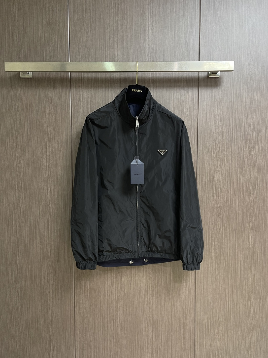 NO:756925,PRADA  The regenerated nylon double-sided stand-collar jacket is made of iconic nylon fabric on both sides. On the basis of the same performance as traditional nylon, the yarn breaking strength reaches 500N, which is far higher than ordinary nylon fabrics. The wear resistance is improved by 30, and it can cope with daily friction and stretching without stress. It weighs only 90g per square meter, making it light and burdenless to wear. The structure is stable and can still be worn after multiple folds.  Quickly restores flatness; has excellent moisture absorption and quick-drying performance, and the water evaporation rate is 2 times faster than ordinary nylon, making daily care easy. One side is classic black, and the other side is deep navy blue, both using matte dyeing technology, with uniform and full color. Both sides can be worn independently, realizing the practical value of 'one garment, two outfits'. All seams are made of 0.4cm wide bias-cut fabric strips  When wrapping, the latitude and longitude slope of the fabric strips is accurate to 45° to ensure no wrinkles during stretching. The edges of the two layers of fabrics are aligned and then folded and stitched. The seams are completely hidden in the interlayer. No raw edges are exposed on the inner and outer sides, and the touch is smooth and delicate. In areas prone to stress such as shoulder seams and armholes, they are manually fixed through 'anchoring points' every 10cm to prevent the two layers of fabrics from facing each other during wearing.  Sliding to ensure a stable shape. Even if the jacket is worn on both sides, it can still maintain a crisp outline and avoid deformation. The stand-up collar is made of double-layer nylon fabric, with a 0.2mm thin strip added to the inner layer. The collar shape is fixed through 3 lines of open stitching. The collar height is controlled at about 7cm, which not only fits the neck curve, but also maintains a three-dimensional crispness, taking into account warmth and neatness. Size S-XL  Size S, shoulder width 51, bust 120, size M, shoulder width 52, bust 124, size L, shoulder width 53, bust 128, size L, shoulder width 53, bust 128, size XL, shoulder width 54, bust 132, length 79.5,,prada,jackets & coats,19860909PRADA 再生尼龙双面穿立领夹克,两面均采用标志性尼龙面料,与传统尼龙同等性能的基础上纱线断裂强度达500N,远超普通尼龙面料,耐磨损性能提升30,应对日常摩擦与拉伸无压力.每平方米重量仅90g,穿着轻盈无负担；结构稳定,多次折叠后仍能快速恢复平整；吸湿速干性能优异,水分蒸发速率比普通尼龙快2倍,日常打理便捷.一面为经典黑色,另一面为深邃藏青色,均采用哑光染色工艺,色泽均匀饱满,两面均可独立穿着,实现'一衣双搭'的实用价值.所有缝份均采用0.4cm宽斜裁布条包裹,布条经纬向斜度精确至45°,确保拉伸时无褶皱.两层面料边缘对齐后折叠缝合,缝线完全隐藏于夹层,内外两面均无毛边外露,触感光滑细腻.在肩缝、袖窿等易受力部位,通过每10cm一处的'锚定点'手工固定,防止两层面料在穿着中相对滑动,确保版型稳定.使夹克即使双面穿着,仍能保持挺括轮廓,避免变形.立领采用双层尼龙面料,内层添加0.2mm薄型衬条,通过3道辑明线固定领型,领高控制在7cm左右,既贴合颈部曲线,又保持立体挺括,兼顾保暖与利落感.尺码S-XL S码肩宽51胸围120 衣长75 M码 肩宽52胸围124 衣长76.5 L码肩宽53胸围128 衣长78 XL码 肩宽54胸围132 衣长79.5,,prada,jackets & coats,,Men's clothing