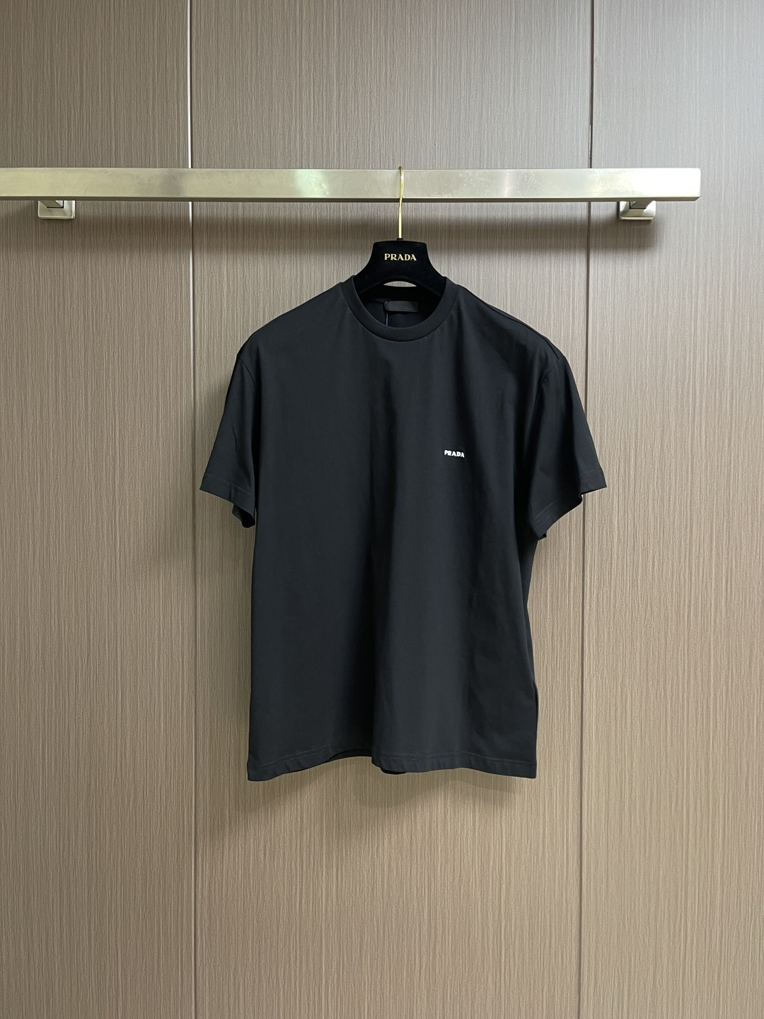 NO:756917,Prada embroidered small logo round neck short-sleeved T-shirt, pure cotton jersey fabric, made of 32-count fine cotton jersey fabric, weight 145g  m2; The neckline adopts 32-count 1x1 rib, and its weight of up to 350gm2 is in sharp contrast with the body. The 32-count yarn is a high count, giving the fabric a delicate and smooth touch; the weight is light and thin, which makes the T-shirt have excellent lightness, breathability and smart drape.  It is very suitable for summer or as an inner layer. Although it is light and thin, the structure of high-count fine cotton can still ensure the durability of the fabric. The high-weight rib provides an extremely thick, strong and highly elastic collar support for the thin body, effectively preventing the collar from loosening and deforming, ensuring the longevity of the entire T-shirt silhouette.  The chest is decorated with simple logo embroidery, and the main body adopts precision stitch embroidery technology; the embroidery is very fine and dense, the letters are clear and the lines and three-dimensional sense are strong. The embroidery thread material is combined with encrypted processing, and the embroidery body has a subtle glossy visual texture; the embroidery effect is three-dimensional and full. The flat embroidery has a simple design of stitch lines, and the embroidery is very precise  The fine stitch method is dense; the overall stitching is fine and the fineness and texture are consistent. The standard version design is made of soft and light knitted fabrics. The standard version ensures a well-fitting cut that can naturally fit the body curve and will not shake due to the clothes being too loose. The overall style is in a simple basic style. Sizes XS-L  XS size shoulder width 50.5 Bust 114 length 70 Small size shoulder width 52 Bust 118 length 72 M size Shoulder width 53.5 Bust 122 length 74 L size Shoulder width 55 Bust 126 length 76,, prada, T-shirt, tees, t-shirt,19860909Prada 刺绣小标志圆领短袖T恤,纯棉平纹针织质面料,采用32支精棉平纹针织面料,克重为145g m2；领口采用32支1x1罗纹,其高达350gm2的克重与衣身形成鲜明对比.32支纱线属于高支数,赋予面料细腻、光滑的触感；克重属于轻薄级别,这使得T恤具有极佳的轻盈感、透气性和灵动垂坠性,非常适合夏季或作为内搭穿着.尽管轻薄,但高支精棉的结构依然能保证面料的耐用性.高克重罗纹为轻薄的衣身提供一个极其厚实、坚固且高弹性的领口支撑,有效防止领口松懈变形,确保了整件T恤的廓形寿命. 胸前饰以简约标识刺绣,主体采用精密挨针绣工艺；刺绣非常精细针法绵密,字母清晰且线条感和立体感强.绣线材质结合加密处理,绣体具有微妙的光泽视觉质感；刺绣效果立体饱满.平绣的挨针走线简约设计,刺绣非常精细针法绵密；整体针脚细密,精细度质感一致.标准版型设计,设计将柔软轻薄的针织面料,标准版型确保了合身的剪裁,能够自然地贴合身体曲线,不会因衣服过于宽松而晃动.整体风格在简约的基础款式中.尺码XS-L XS码肩宽50.5 胸围114衣长70  S码肩宽52 胸围118衣长72  M码 肩宽53.5 胸围122衣长74 L码 肩宽55 胸围126衣长76,,prada,T-shirt,tees，t-shirt,,Men's clothing