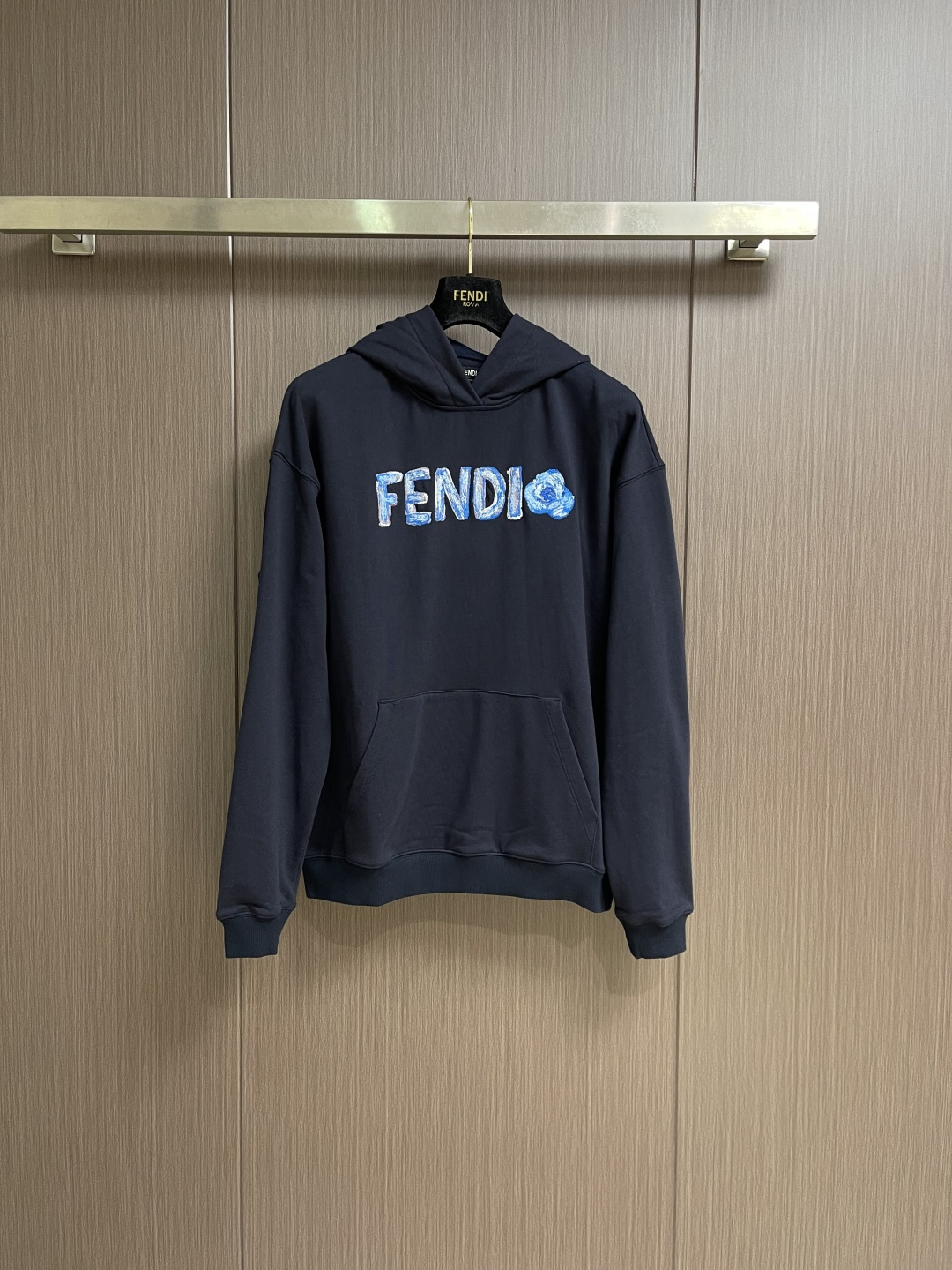 NO:756935,FENDI  The hooded sweatshirt with embroidery is made of single-sided fish-scale fabric woven with cotton as the base. The front is a smooth knitted surface, and the skin-contacting surface is formed into three-dimensional terry through the floating knitting technology of the knitting machine, which increases the fluffiness and delicate touch. The terry structure absorbs large amounts of water and evaporates quickly. After pre-shrinking treatment, the shrinkage rate is less than 2, ensuring the stability of the size of the garment. The dark blue dyeing and finishing uses reactive dyes, the color is rich and full, and it is not easy to fade after repeated washing. 'Fd' on the chest  Flower' pattern is precision embroidered by Japanese Tajima embroidery machine, integrating multi-color gradient and three-dimensional texture to present a unique watercolor effect. Letters and flower patterns use different shades of blue and white gradient embroidery thread, with a natural transition from light blue to indigo, simulating the layering of watercolor blooming. The fineness of each embroidery thread is 4  0S2, through high-density embroidery of 1,200 stitches, ensures even fusion of colors without obvious color block boundaries. The center of the flower forms a full three-dimensional texture through the stacking of yarns, simulating the soft visual sense of petals. The edges are outlined with flat embroidery, with stitches as fine as hair, and smooth and natural lines.  .The edges of the letters are embroidered with 'virtual and solid needles', and some areas are left blank to create the 'flying white' effect of watercolor paintings and enhance the flexibility of the pattern. The kangaroo pocket on the chest is made of twill cotton material. The edge of the bag is folded in 1cm and then double-stitched with topstitching. The stitch spacing is 0.3cm to ensure that the bag shape is three-dimensional and crisp. It can accommodate anything  It is a body-worn item that combines practicality and decoration. The cuffs and hem are all made of 1x1 rib of the same color. The raw material is 97% cotton + 3% spandex blend. The thickness is 2.5mm. It has excellent resilience and fits the wrist and waist closely to prevent cold wind from entering while maintaining the neat outline of the sweatshirt. Sizes S-XL  Size S, shoulder width 57, bust 118, size M, shoulder width 58, bust 122, size L, shoulder width 59, bust 126, size L, shoulder width 59, bust 126, size XL, shoulder width 60, bust 130, length 70,,fendi,hoodie,sweatshirts,hats,19860909FENDI 饰刺绣连帽卫衣,选用棉为基底编织而成的单面鱼鳞布面料,正面为平滑的针织面,触肤面通过针织机的浮线编织技术形成立体的毛圈,增加蓬松感,同时触感细腻.毛圈结构吸水量大且蒸发快,经过预缩处理之后,缩水率低于2,确保成衣尺寸稳定.深蓝色染整采用活性染料,色泽浓郁饱满,多次洗涤不易褪色.胸前'Fd Flower'图案采用日本田岛绣花机精密刺绣,融合多色渐变与立体肌理,呈现独特的水彩效果.字母与花朵图案使用不同深浅的蓝白渐变绣线,从浅蓝到靛蓝自然过渡,模拟水彩晕染的层次感.每根绣线细度为40S2,通过1200针英寸的高密度刺绣,确保色彩均匀融合,无明显色块边界,花朵中心处通过纱线的堆叠形成饱满的立体肌理,模拟花瓣的柔软视觉感官.边缘则以平绣勾勒轮廓,针脚细密如发丝,线条流畅自然.字母边缘采用'虚实针'刺绣,部分区域留白,营造水彩画的'飞白'效果,增强图案的灵动性.胸前袋鼠口袋采用斜纹棉料,袋口边缘内折1cm后双线辑明线,线迹间距0.3cm,确保袋型立体挺括.可容纳随身物品,兼顾实用性与装饰性.袖口与下摆均采用同色系1x1罗纹,原料为97％棉＋3％氨纶混纺,厚度达2.5mm,回弹性优异,紧密贴合手腕与腰部,防止冷风灌入,同时保持卫衣的利落轮廓.尺码S-XL S码肩宽57胸围118 衣长67 M码 肩宽58胸围122 衣长68 L码肩宽59胸围126 衣长69 XL码 肩宽60胸围130 衣长70,,fendi,hoodie,sweatshirts,hats,,Men's clothing