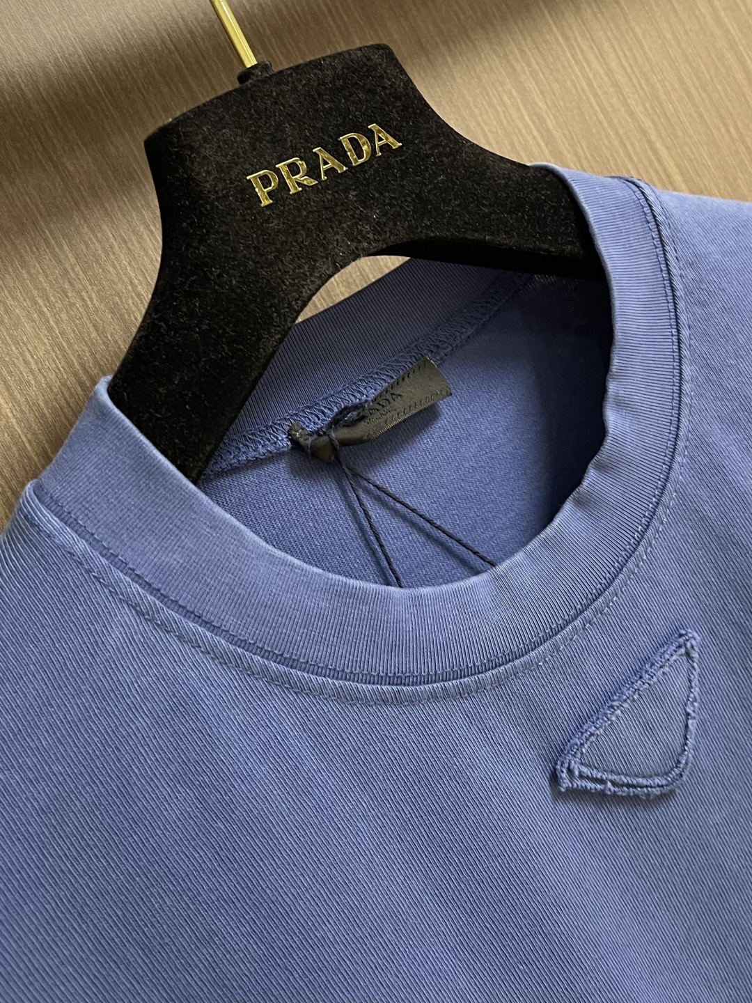 Prada 蓝三角圆领长袖T恤，采用12支精棉平纹针织面料，克重为230gm2；搭配32支双纱高罗纹，克