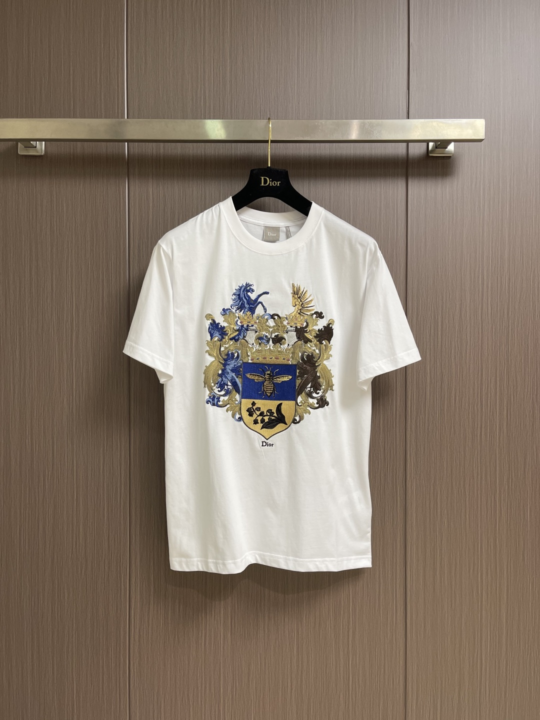 NO:775957,DIOR  The Royal emblem heavily embroidered round neck short-sleeved T-shirt is made of imported high-count combed long-staple cotton fabrics customized by the brand. It has been processed by pre-shrunk shaping and enzyme washing to maintain a neat and smooth shape for long-term wear; the classic reinforced round neck adopts high-density thread hemming technology, and the collar has strong elasticity, which is not easy to loosen and collapse after repeated washing. It fits the neck line and is simple and elegant, suitable for all kinds of wear styles; the front of the body adopts the royal emblem theme multi-color three-dimensional embroidery technology, Jun  The horse crown shield and other retro elements are sewn with layered high-density embroidery. The blue, black and gold three-color embroidery threads are clearly layered, the stitches are dense and full, the pattern is three-dimensional and full without jumpers, the details are complex and elegant, and the retro atmosphere and luxurious texture are combined; at the hem  It is embellished with brand letter embroidery, and the craftsmanship is exquisite and low-key to echo the overall design; the cuffs and hem are double-threaded with precision stitching, the stitching is even and smooth, and the seam is strong and wear-resistant, eliminating the problem of off-line and greatly improving the durability of clothing. Size XS-L  size19860909DIOR 皇家徽章重工刺绣圆领短袖T恤,甄选品牌定制进口高支精梳长绒棉面料打造,经过预缩定型与酵素水洗双重工艺处理,长期穿着依旧保持利落平整的版型；经典加固圆领采用高密度螺纹收边工艺,领口回弹性强,反复洗涤穿着不易松垮塌陷,贴合颈部线条,简约大气适配各类穿搭风格；衣身正面采用皇家徽章主题多色立体刺绣工艺,骏马皇冠盾牌等复古元素采用分层式高密度刺绣缝制,蓝黑金三色绣线层次分明,针脚密实饱满,图案立体饱满无跳线,细节繁复考究,复古氛围感与奢华质感兼具；下摆处点缀品牌字母刺绣,工艺精致低调呼应整体设计；袖口与下摆采用双线包缝精密走线,针脚均匀流畅,锁边牢固耐磨,杜绝脱线问题,大幅提升衣物耐用度.尺码XS-L XS码胸围104肩宽47.5衣长72 S码 胸围108肩宽49 衣长74 M码胸围112 肩宽50.5衣长76 L码 胸围116 肩宽52 衣长78,,dior,T-shirt,tees，t-shirt,,Men's clothing