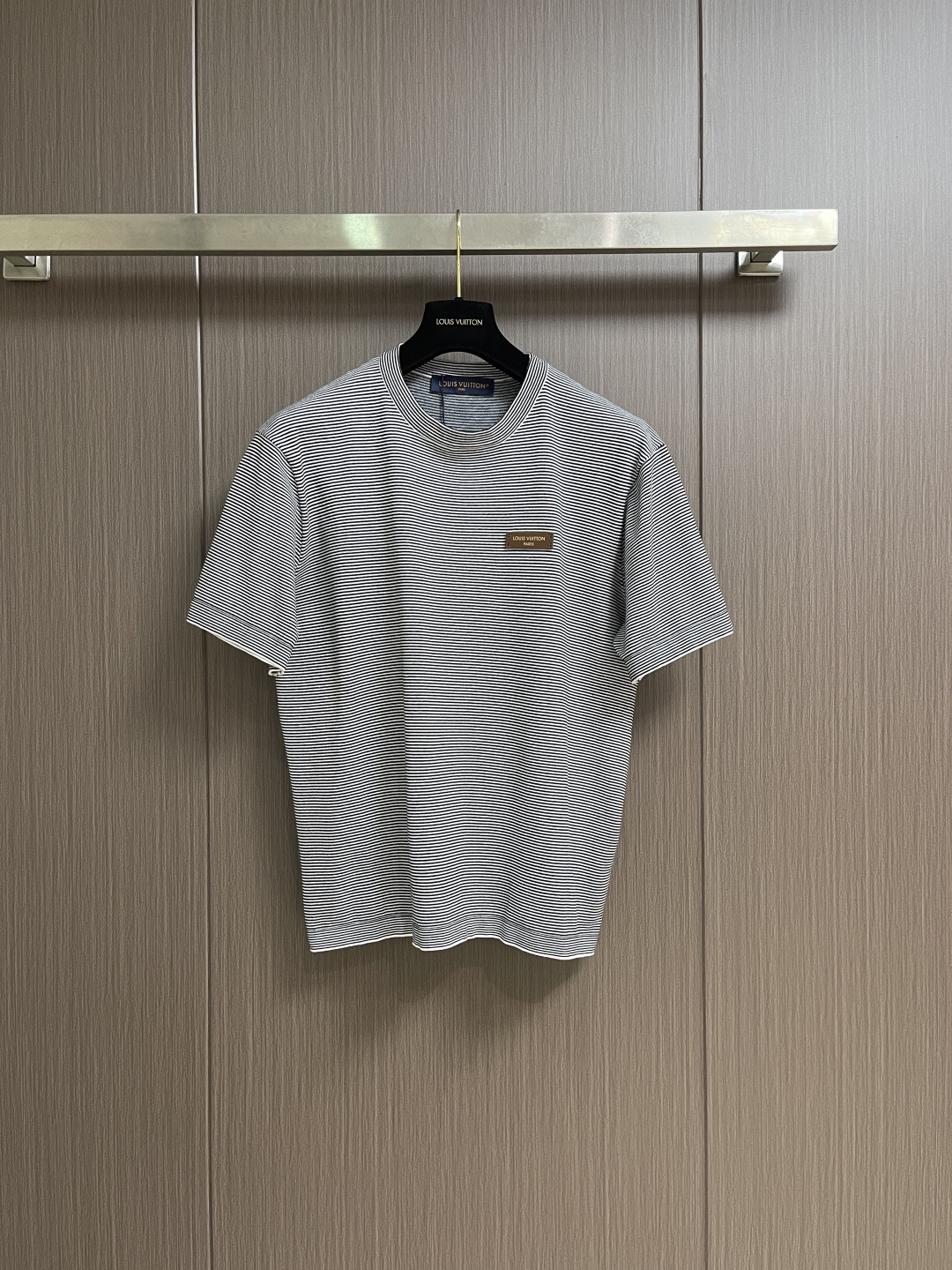 NO:775977,LV  2026SS summer series Logo logo pinstripe short-sleeved round neck T-shirt, made of high-count double-ply combed cotton fabric, treated with liquid ammonia mercerization and pre-shrunk, with a delicate and skin-friendly touch, excellent breathability and perspiration, and is not easy to pill and deform after long-term wear. It is suitable for many summers  For scene wear. Precision-dyed weaving technology is used to create a fine stripe texture. The spacing between the stripes is precise and uniform. The color fastness is full and the bright texture remains after repeated washing. The neckline is reinforced with double-layer high-elastic ribbing and is matched with the same color hemming. It will not loosen after long-term wear and fits well.  The neck is more comfortable. The wiring follows the brand's strict standards, using four-needle and six-thread boneless suture technology, and double seams at stress-bearing areas such as the rotator cuff and side seams to eliminate the risk of thread opening. The left chest is decorated with the brand's iconic leather logo, which is fixed by high-temperature lamination.  The stitching is fine and three-dimensional, and the details show high-end texture. The overall tailoring is loose and neat, taking into account both casualness and brand recognition. It is a luxury summer item with both practicality and design. The overall wiring is straight and delicate, the fabric is comfortable and soft, and the color is consistent without color difference.  It can be matched with the same style to create a fashionable look, and can be used in various occasions. Customized accessories, complete with three standards, same style for men and women!  Size S-XL S size bust 108 shoulder width 44 length 66 M size bust 112 shoulder width 46 length 68 L size bust 116 shoulder width 48 length 7019860909LV 2026SS夏季系列Logo标牌细条纹短袖圆领T恤,甄选高支双股精梳棉面料,经液氨丝光与预缩水处理,触感细腻亲肤,透气排汗性优异,久穿不易起球变形,适配夏日多场景穿着.采用精密色织工艺打造细条纹肌理,条纹间距精准统一,色牢度拉满,反复洗涤仍保持鲜亮质感.领口采用双层高弹罗纹加固工艺,搭配同色系包边,久穿不松垮,贴合颈部更舒适.走线遵循品牌严苛标准,采用四针六线无骨缝合技术,肩袖、侧缝等受力处双重锁边,杜绝开线隐患.左胸饰以品牌标志性皮质Logo标牌,经高温压合工艺固定,针脚细密立体,细节处彰显高级质感,整体剪裁宽松利落,兼顾休闲感与品牌辨识度,是兼具实穿性与设计感的奢品夏日单品.整体走线平直细腻,面料舒适柔软,颜色一致无色差 能与同款搭配营造时尚造型,驾驭各种场合,定制辅料,三标齐全,男女同款！尺码S-XL S码 胸围108 肩宽44衣长66 M码胸围112肩宽46衣长68 L码 胸围116肩宽48衣长70 XL码胸围120 肩宽50 衣长72,,louis vuitton,T-shirt,tees，t-shirt,,Men's clothing