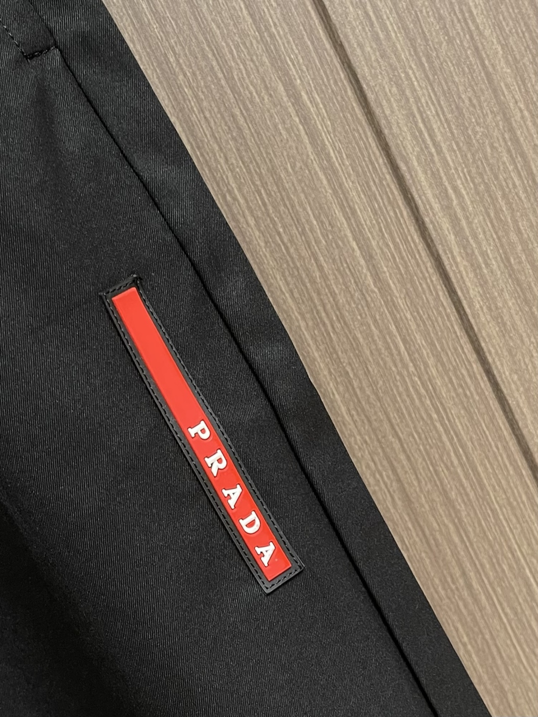 Prada 三角标户外机能风黑白休闲裤，经典倒三角金属标+立体刺绣Logo双重加持，后腰口袋的三角铭牌是