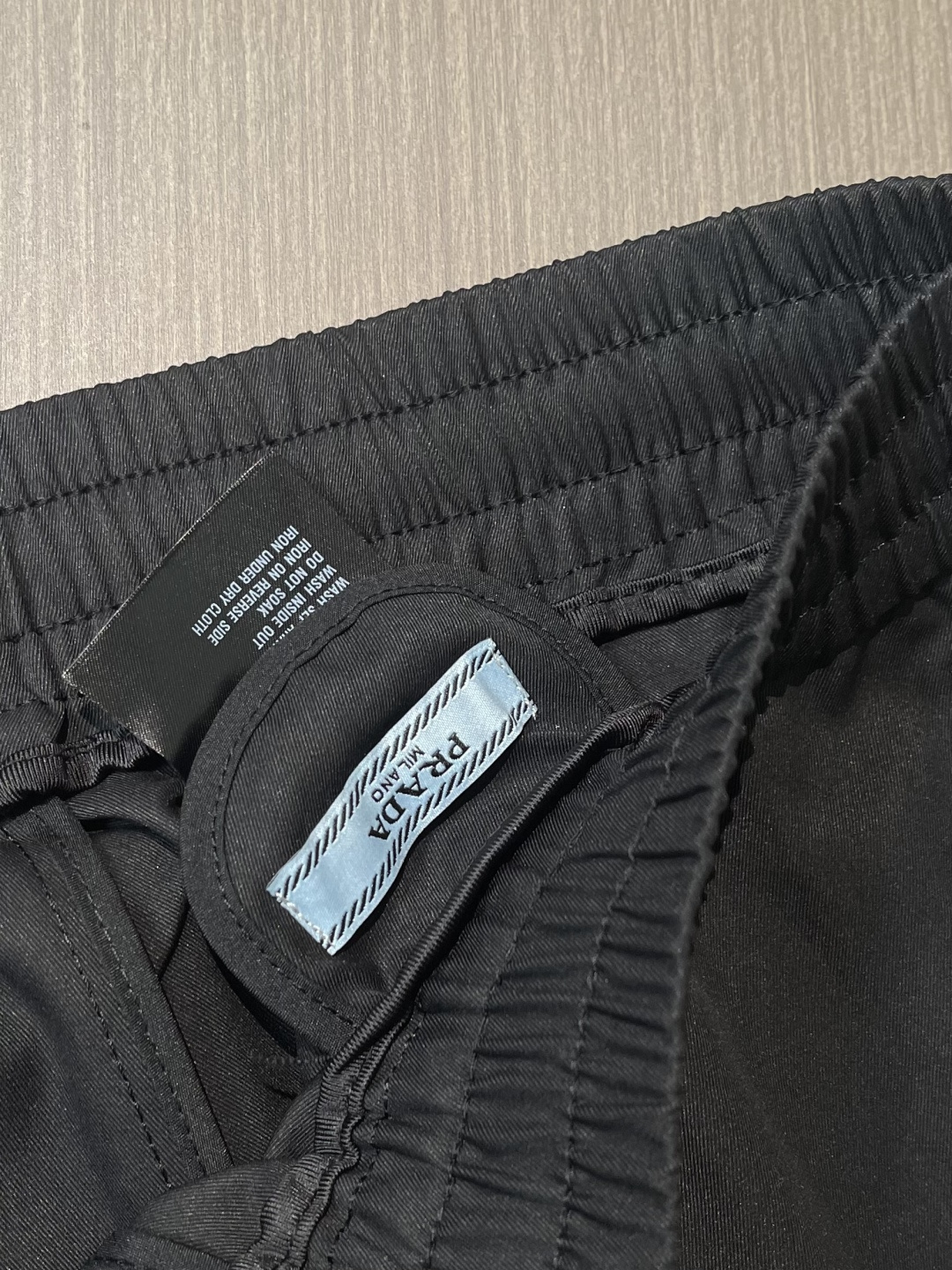 Prada 三角标户外机能风黑白休闲裤，经典倒三角金属标+立体刺绣Logo双重加持，后腰口袋的三角铭牌是