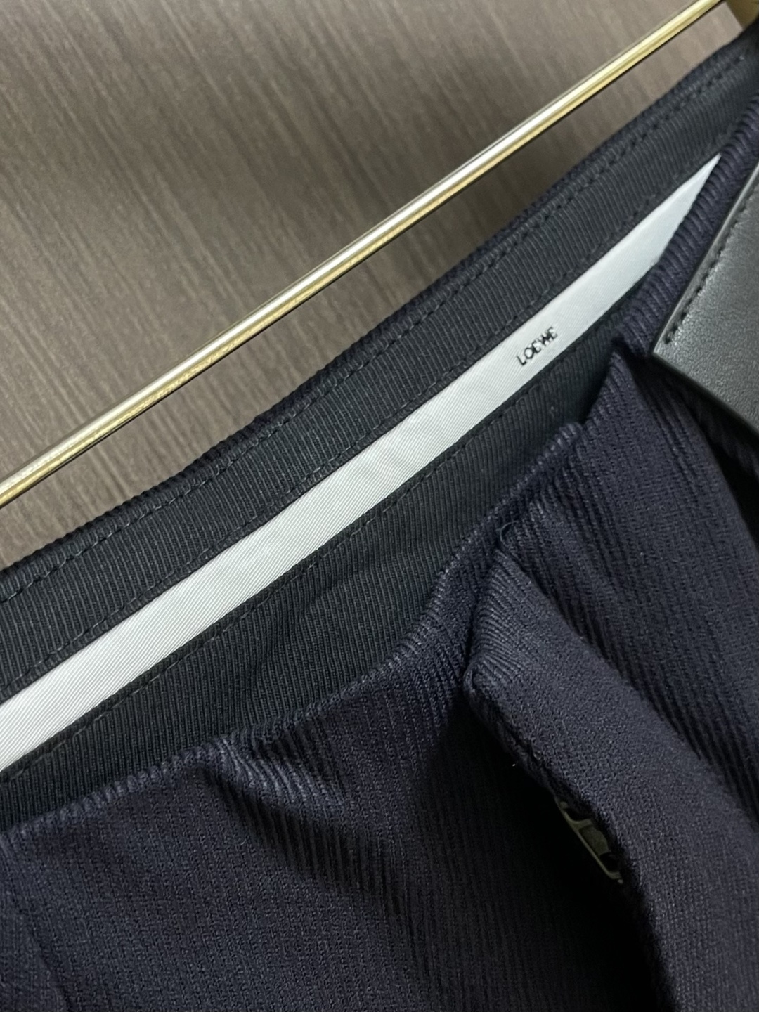 Loewe 皮牌休闲裤，定制丝光雾面羊毛，以雾感深海军蓝为主色调，腰头正面饰有LOE 压纹皮革贴片，与纽