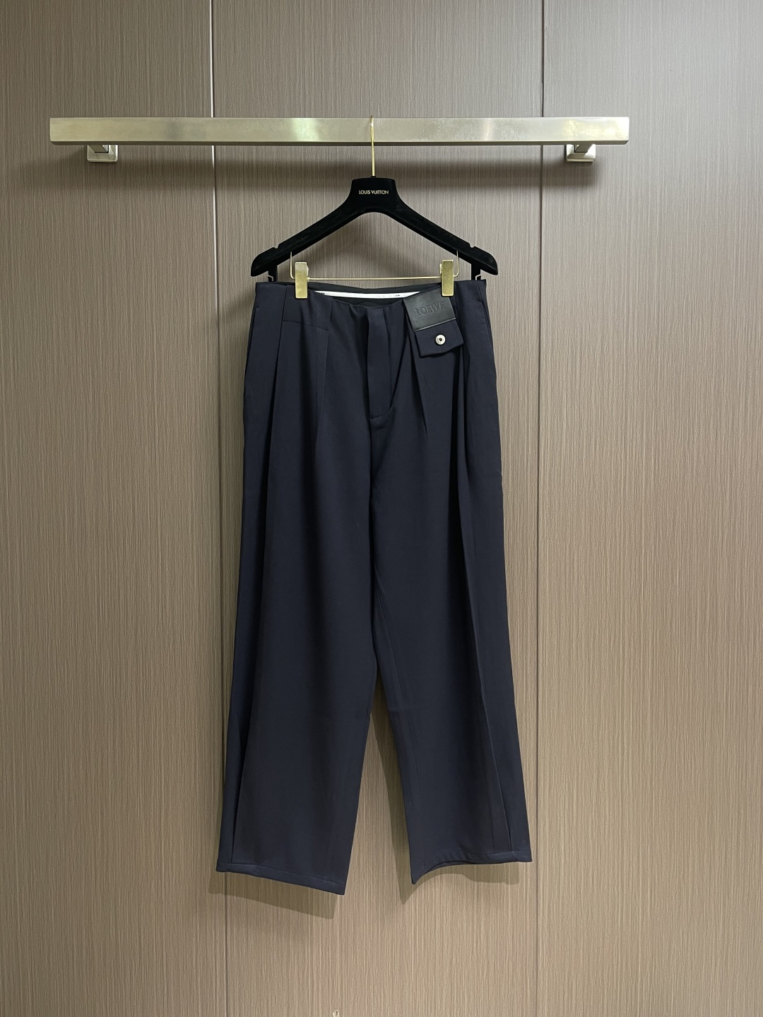 Loewe 皮牌休闲裤，定制丝光雾面羊毛，以雾感深海军蓝为主色调，腰头正面饰有LOE 压纹皮革贴片，与纽