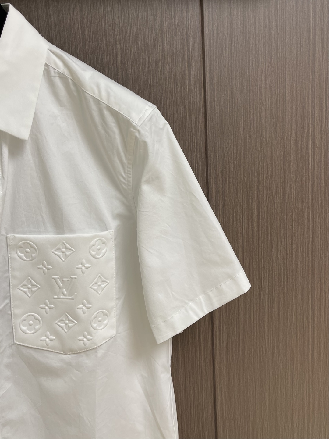 LV 压花口袋翻领短袖衬衫，织物正面斜纹纹路明显，反面比较模糊。经纬向均用单纱，线密度接近，织物经密略高