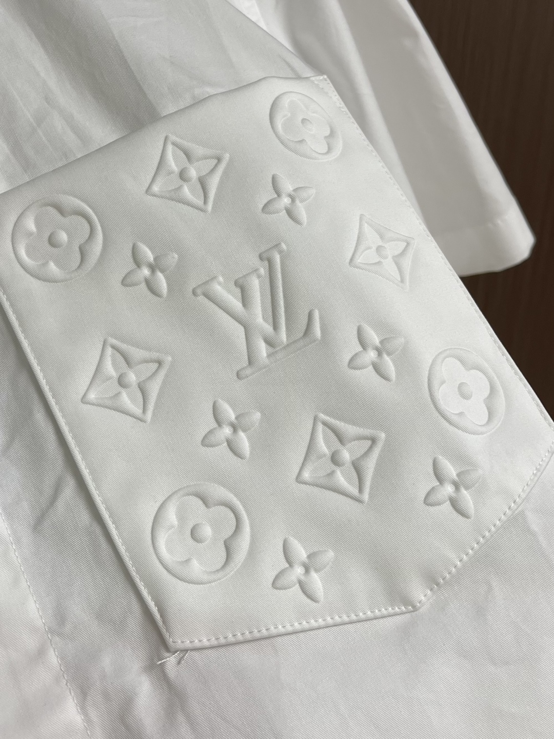 LV 压花口袋翻领短袖衬衫，织物正面斜纹纹路明显，反面比较模糊。经纬向均用单纱，线密度接近，织物经密略高