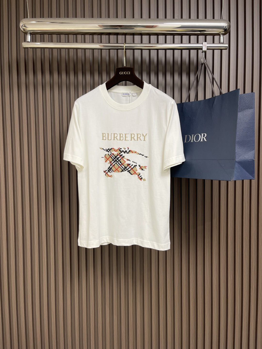 NO:144680,Burberry plaid war horse short-sleeved T-shirt, using 15s fine cotton plain patterns, 230g; matched with 32s double yarn thread, 300g. Through dense laying of fine particles, a three-dimensional texture similar to rice grains is formed; the pixelated texture of cross stitch can echo the geometric regularity of the plaid, emphasizing the sense of flatness of the plane and enhancing the retro feeling. The combination of rice grain embroidery and cross stitch creates visual memory points through craft contrast to ensure the flatness of the embroidery; the density of the stitches must be accurately matched with the logo lines. The overall line is straight and delicate, the fabric is comfortable and soft, and the color is consistent and has no color difference. It can be matched with the same style to create a fashionable look, and can handle various occasions, customize auxiliary materials, complete three standards, and the same style for men and women!  Size XS-L, Burberry, T-shirt,tees, t-shirt,alexander wang19860909Burberry 格子战马短袖T恤,采用15s精棉平纹,230g；搭配 32s双纱拉架螺纹,300g.通过细小颗粒密铺,形成类似米粒的立体质感；以十字绣的像素化质感能呼应格纹的几何规律性,强调平面几何秩序感和增强复古感.米粒刺绣与十字绣的搭配,通过工艺反差营造视觉记忆点.确保刺绣平整度；针脚密度需与徽标线条精准匹配.整体走线平直细腻,面料舒适柔软,颜色一致无色差 能与同款搭配营造时尚造型,驾驭各种场合,定制辅料,三标齐全,男女同款！尺码XS-L,,burberry,T-shirt,tees，t-shirt,alexander wang,Men's clothing