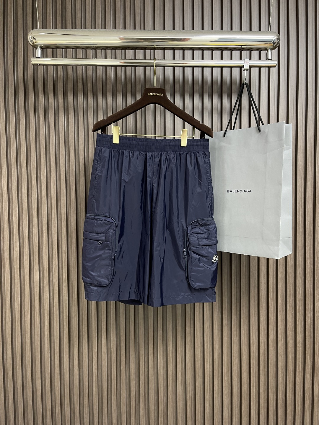 NO:162281,Moner's three-party co-branded nylon shorts are made of custom nylon nylon fabric. They create tear-resistant surfaces through high-density warp and weaving technology. The single layer weight is precisely controlled at about 150gm2, making it lightweight, without burden and smooth to touch. The nylon itself has good elasticity and is not easy to wrinkle, maintaining a long-term flatness. It has a certain resistance to acids, alkalis, oils, etc. in daily life, and is easy to clean and repair. The lining is also made of nylon. Because it requires good breathability, it adopts a fine mesh design.  Smooth and skin-friendly, it is not easy to pill, damage due to long-term friction, and extends service life. The work pocket on the side of the decorative seal has a seamless folding structure, which is a three-dimensional storage space after being unfolded. When folded, it is closed by a hidden zipper to form a compact storage bag. The main logo patch is molded with liquid silicone, with a thickness of 2.2mm, and the edge simulates the chrome plating effect of the car logo. The patch stitching is alternately knitted with polyester thread, and the number of needles per inch is 12 stitches per inch, ensuring that it does not fall off after long-term washing. Size S-XL, shorts, alexander  wang19860909Moner三方联名可收纳尼龙短裤,选用定制锦纶尼龙面料制成,通过高密度经纬编织技术打造抗撕裂表面,单层克重精准控制在150gm2左右,使其质地轻盈,穿着无负担且触感顺滑.锦纶本身具有良好的弹性且不易起皱,保持长久的平整度.日常生活中对酸、碱、油污等有一定的抵抗力,易于清洁打理.内衬同样选用锦纶,因需要良好的透气性,故采用细密网眼设计.贴身穿着顺滑亲肤,不易因长时间摩擦导致起球,破损,延长使用寿命.饰章侧工装口袋内置无缝折叠结构,展开后为立体储物空间,折叠时通过隐藏式拉链闭合,形成紧凑的收纳包.主标识贴片采用液态硅胶模压成型,厚度2.2mm,边缘模拟车标镀铬效果,贴片缝线以涤纶线交替编织,每英寸针数12针,确保长期水洗不脱落.尺码S-XL,,shorts,alexander wang,Men's clothing