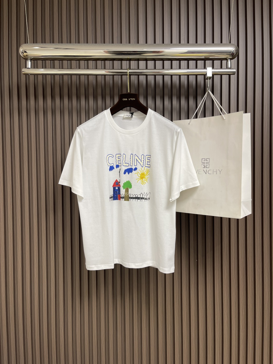 NO:455912,Celine Children's Fun Painting Print Round Neck Short-Sleeve T-shirt, Pure Cotton Fabric, Children's Fun Painting Print, Loose Style, Round Neck Short-Sleeve, Ribbed Collar, Full Set of Auxiliary Materials, 50S Double-Strand Mercerated Cotton, 165g gram weight; matched with 32S  1x1 tie-up thread, 300g. The thinner the yarn, the higher the number of branches, the fabric made is usually softer, smoother and finer. Two yarns are used and twisted together. This can enhance the strength and durability of the fabric and make the feel more full. The cotton fiber is treated with a concentrated caustic soda solution to make the fiber surface smoother and increase the gloss and softness of the fabric. Children's fun graffiti painting printing, adjust the same color material according to the original color special, and choose high elastic tie-up glue printing. Increase the elasticity of the printing part, and the penetration is strong, especially on all cotton fabrics. The details between the printing are very well processed, without burrs and cross-border marks.  By technically processing the printed screen, the patterned paste can pass through the fabric, with strong permeability and clear and visible fabric texture. The dots are used in the local area, and the distribution of dots is very dense, so the printed pattern has extremely high clarity and resolution. High-density dot paste printing technology is used to print various complex patterns and textures on clothing. Due to the special properties of the paste, the printed pattern has a certain attractiveness, unique visual effect, and a delicate touch. Size S-M-L, celine, T-shirt, tees, t-shirt, alexander  wang19860909Celine 童趣绘画印花圆领短袖T恤,纯棉质面料、童趣涂鸦绘画印花、宽松版型、圆领短袖、衣领饰有罗纹、全套辅料配备 采用50S双股丝光棉,克重165g；搭配32S 1x1拉架螺纹,300g.纱线越细,支数越高,制成的面料通常越柔软、光滑且精细.使用了两根纱线并捻在一起.这样做可以增强面料的强度和耐用性,手感更加饱满.棉纤维经过浓烧碱溶液处理,使纤维表面变得光滑增加了面料的光泽度和柔软度.童趣涂鸦绘画印花,根据原色特调同色胶浆材质,选择高弹拉架胶浆印刷.增加印花部位弹力,同时渗透力色牢度较强,尤其在全棉面料上效果更好.印花之间细节处理非常到位,无毛边及过界痕迹.经过对印刷网版进行技术处理,使有图案的地方浆料能够透过到织物上,渗透性强且面料纹路清晰可见.局部采用网点浆印刷技术,网点的分布非常密集因此印刷出的图案具有极高的清晰度和分辨率.利用高密度网点浆印花技术在服装上印刷出各种复杂的图案和纹理,由于浆料的特殊性质,印刷后的图案具有一定的吸引力,视觉效果独特,而且触感细腻.尺码S-M-L,,celine,T-shirt,tees，t-shirt,alexander wang,Men's clothing