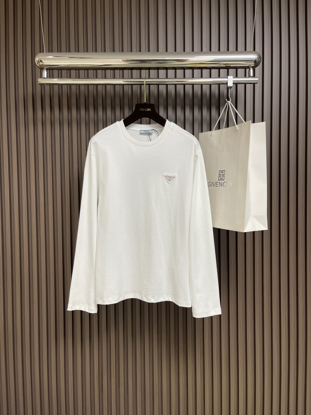 NO:499915,PRADA triangle logo round neck long-sleeved T-shirt, which is made of high-quality pure cotton, is soft and skin-friendly and has a special texture. It is smooth but has a solid thickness. It is not the kind of cheap product that can be deformed at once!  The letters on the triangle mark on the chest are clear and three-dimensional, with a heavy texture. When you put them on the white T, you will instantly fill the sense of high-end, low-key and recognizable!  The cuffs and hem are treated with particularly neat curling edges, and the seams are as uniform as the machine has calculated carefully. No matter how many times you wash them, you won’t deform the curling edges!  The cuffs and hem are treated with particularly neat curling edges. They will not deform and curl the edges even if washed a few times. They can be matched with many types of clothing to create a fashionable look, customized accessories, complete three standards, the same style as men and women!  Size S-XL, prada,tees, t-shirt,alexander wang19860909PRADA 三角标识标识圆领长袖T恤,采用高品质纯棉,软糯亲肤还特显质感,光溜溜的但又有扎实的厚度,不是那种一扯就变形的廉价货！胸口三角标上的字母清晰立体,质感沉甸甸的,往白T上一镶,瞬间把高级感拉满,低调又有辨识度！袖口和下摆的处理,卷边特别工整,缝线均匀得像机器精密计算过,水洗多少次都不会变形翘边！袖口和下摆的处理,卷边特别工整,水洗少次都不会变形翘边,能与多类型服饰搭配营造时尚造型,定制辅料,三标齐全,男女同款！尺码S-XL,,prada,tees，t-shirt,alexander wang,Men's clothing