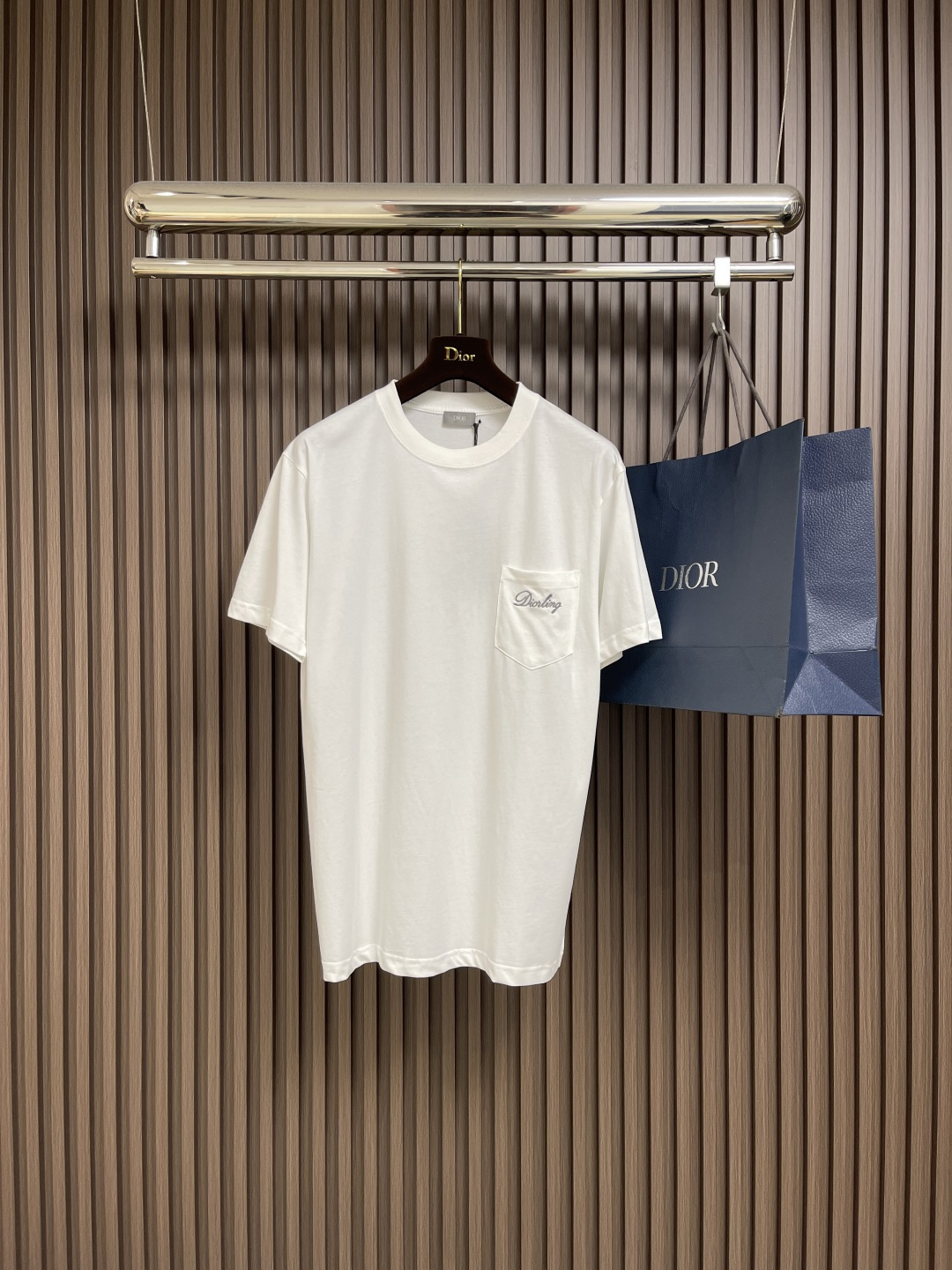 NO:504511,Dior cotton jersey round neck T-shirt, this T-shirt is a new product in the 2025 winter series. It is decorated with Dior Love embroidery inspired by Dior archives, paying tribute to Dior. It is carefully crafted from gray cotton jersey fabric with ribbed round neck. The regular version can be easily matched with finely tailored and oversized versions. The chest is decorated with Dior Love embroidery  Ribbed round neck, embroidery logo on the chest pocket, sewn with three-dimensional needle-to-face embroidery process. The multi-layered needle arrangement brings a slightly convex three-dimensional visual effect, with clear and smooth details, and rounded letter edges, improving the overall delicateness and artistic sense. (The embroidery pattern is stable and firm on the soft cloth surface, not easy to fall off, showing the fine control of embroidery texture and texture of Dior Workshop, which is a perfect combination of brand craftsmanship and design concept.) High-spec 24 tight yarn 185g cotton fabric, woven using precision knitting technology. The fabric feels soft and delicate, comfortable to touch the skin, has good breathability and elasticity, and takes into account anti-allergic and wear resistance, showing the quality, thickness and skin-friendly feeling that high-grade knitted cotton should have. The double yarn ribbed neckline splicing makes the details more textured, fit better and not easily deformed, and it is more durable for daily wear.  Size XS-L,,dior,dior,tees,t-shirt,alexander wang19860909Dior 棉质竹节平纹针织圆领T恤,这款T恤是二零二五冬季系列新品,饰以灵感源自迪奥档案的迪奥之爱刺绣,向迪奥承传致敬.采用灰色棉质竹节平纹针织面料精心制作,搭配罗纹圆领.常规版型,可与精裁和超大版型轻松搭配.胸前饰以迪奥之爱刺绣 罗纹圆领,胸前口袋刺绣标识,采用立体挨针绣线工艺缝制.多层次的针法排列带来微凸的立体视觉效果,细节清晰流畅,字母边缘收针圆润,提升整体细腻度与艺术感.（刺绣图案在柔软布面上稳定牢固,不易脱线,展现迪奥工坊对于刺绣纹理与质感的精细把控,是品牌工艺与设计理念的完美结合.)高规格24支紧密纱185g棉质面料,采用精密针织工艺织就.面料手感柔软细腻,触肤舒适,具备良好的透气性与弹性,同时兼顾抗敏、耐磨等性能,展现出高级针织棉料应有的品质厚度与亲肤感. 双纱罗纹领口拼接,细节处更显质感,贴合度佳且不易变形,日常穿着更为耐久. 尺码XS-L,,dior,dior,tees，t-shirt,alexander wang,Men's clothing