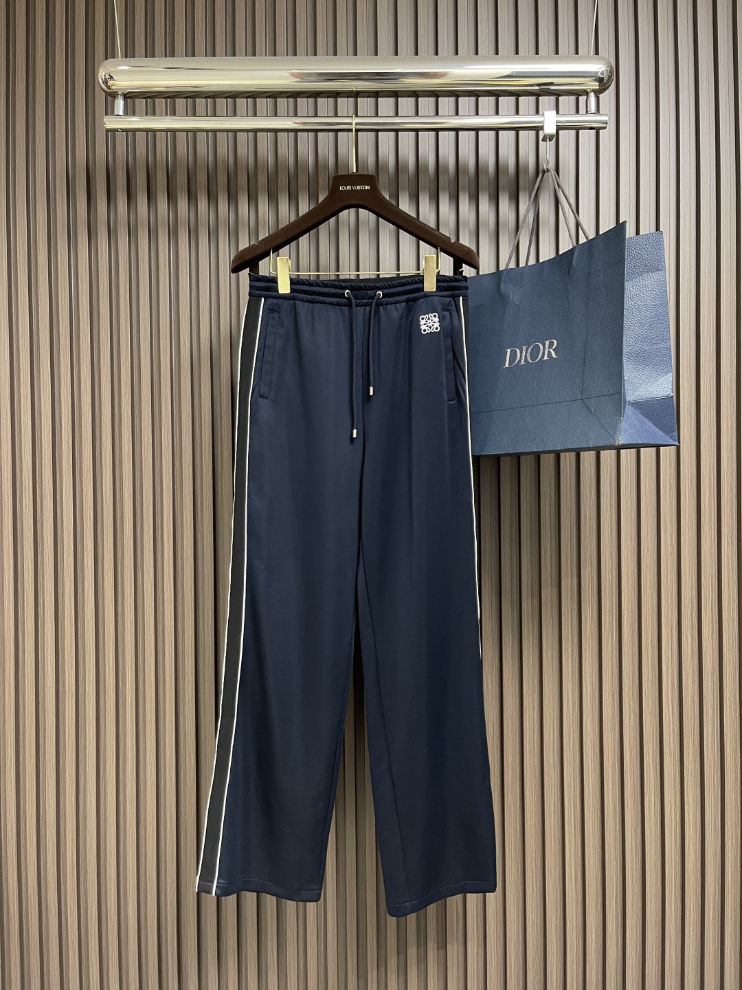 NO:516725,Loewe Contrast color webbing casual trousers, made of technological jersey knitted fabric, decorated with contrasting stripes and contrasting Anagram embroidery. The fabric consists of a sports material of polyester fiber. Before spinning, polyester fiber is fixed-dyeed dyed with imported environmentally friendly dyes, which has high strength and elastic recovery ability, so it is firm and durable, wrinkle-resistant and hot-resistant. The main body of the logo pattern uses white embroidery thread to create a precision needle embroidery process; the embroidery is very fine and dense. The embroidery thread is combined with encryption processing, and the embroidery body is It has a subtle matte visual texture. The embroidery surface is specially treated to make the silk thread smooth. Then, the overall embroidery pattern is finished with a flat embroidery needle method. The mid-waist vertical sports trousers style, the loose trousers are not limited to the figure and legs, and the inclusive vertical effect is significant. The waist and mid-waist trousers are decorated with a webbing design. The middle pleats and side pockets are connected to the trousers, and there are zippered oblique insertion pockets on both sides and back. The oblique insertion insertion insertion insertion insertion. Size XS-L,,loewe,alexander wang19860909Loewe 撞色织带休闲长裤,采用科技平纹针织面料,饰有对对比色条纹和对比色Anagram刺绣.面料由聚酯纤维的运动材质组成.聚酯纤维纺前采用进口环保材质染料定染加工,具有较高的强度与弹性恢复能力,因此牢固耐用、抗皱免烫.标识图案主体采用白色绣线打造精密挨针绣工艺；刺绣非常精细针法绵密.采用亚麻材质绣线结合加密处理,绣体具有微妙的哑光视觉质感.刺绣表面进行特殊处理,使丝线平整顺滑,接着利用平绣的针法,进行整体刺绣图案收尾.中腰垂直款运动长裤版型,宽松裤管不限身材与腿型,包容性强垂直效果显著.连腰中腰裤管两侧饰有人字织带设计.连接裤中褶与侧兜,两侧及后幅有拉链斜插袋,斜插式插手置物.尺码XS-L,,loewe,alexander wang,Men's clothing