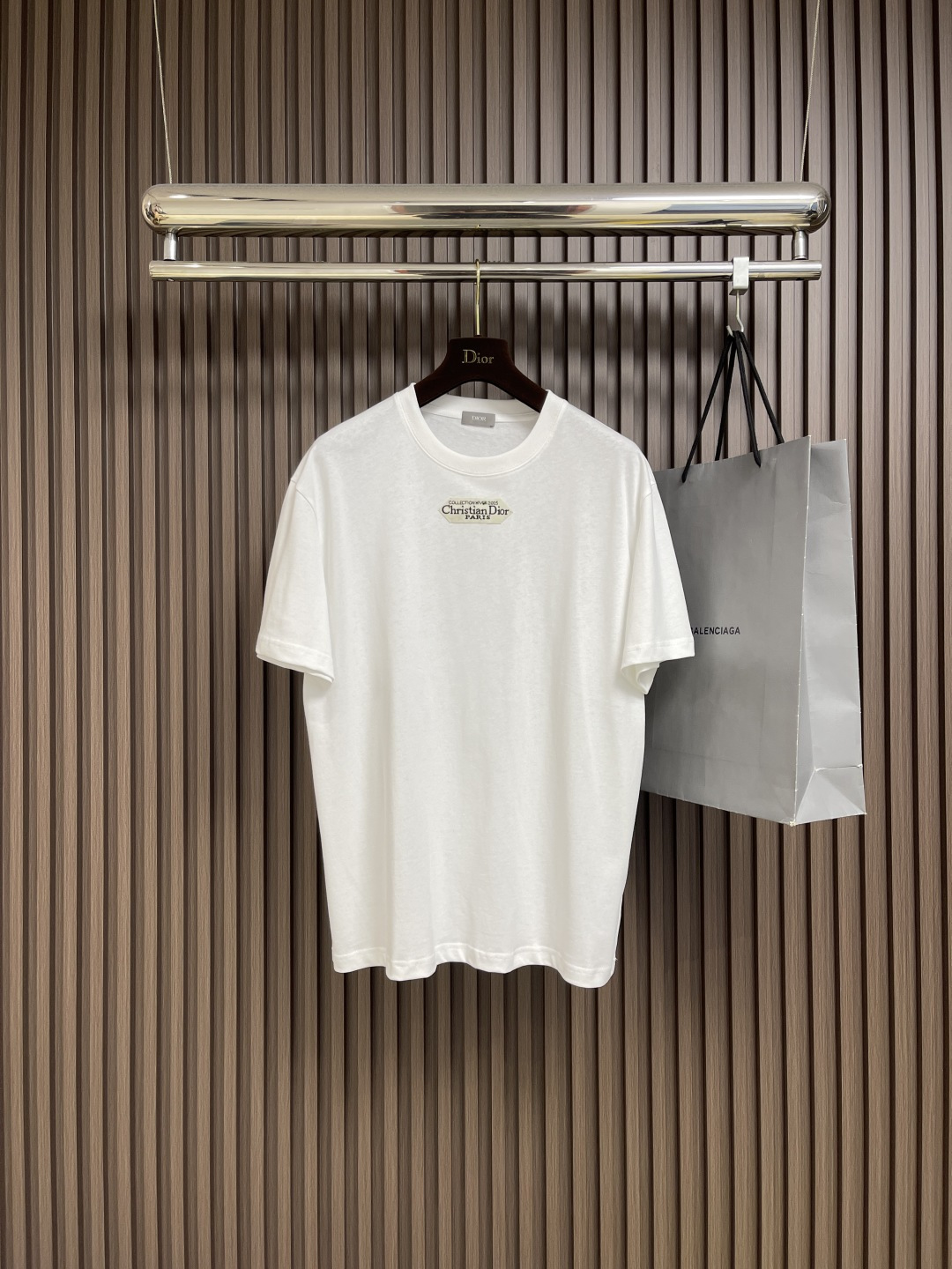 NO:523643,Dior small-label round neck short-sleeved T-shirt, cotton jersey fabric, chest with small labels, ribbed round neck and cuffs, conventional design, full set of auxiliary materials, cotton jersey fabric, 24S special-spun tight cotton fabric, 185g; matched with 32S double yarn thread, 300g. The tight spinning strength is higher than traditional single yarn, and the single fibers in the tight yarn are arranged tightly, which helps to improve the strength of the yarn. The ends of the fibers are twisted into the yarn, so the yarn is very tight, and the yarn looks smooth and there are fewer hair feathers. The tight spinning yarn has higher strength and fewer hair feathers, which is not easy to cause hair fur. The chest is decorated with a small label, and the 'Paris' on the label emphasizes the brand's French bloodline and fashion tradition; it is presented through the jacquard woven label process, reflecting the brand's pursuit of high-end craftsmanship and classic aesthetics. Through the digital jacquard loom  The brand text pattern is directly woven into the label, with clear texture and no burrs on the edges, which makes it more three-dimensional and durable than ordinary printed labels. High-string cotton material is used to ensure soft touch while maintaining a crispness; classic white black characters are interspersed, improving the texture through the luster of the yarn itself. The standard round neck style and the neckline are rounded curved, suitable for all face shapes and figures; the sleeves are moderate and just over the elbow, showing a capable and neat image. Slim-fitting cut can show the wearer's figure curve while not losing comfort. The neckline, cuffs, hem and other parts are sewn with fine double needle thread. Size XS-L,,dior,T-shirt,tees,t-shirt,alexander wang19860909Dior 小标签圆领短袖T恤,棉质平纹针织面料、胸前饰以小标签、罗纹圆领和袖口、常规版型设计、全套辅料,棉质平纹针织面料,采用24S特纺紧密棉面料,185g；搭配32S双纱螺纹,300g.紧密纺强力比传统单纱高,紧密纱中的单纤维排列紧密,有助于提高纱线的强力.纤维的端头均捻入纱线内,因此成纱非常紧密,纱线外观光洁毛羽少.紧密纺纱线强力较高毛羽较少,不易产生磨毛的现象.胸前饰以小标签,标签上的“Paris”强调品牌的法式血统与时装传统；通过提花织唛工艺呈现,体现了品牌对高级工艺与经典美学的追求.通过数码提花织机 将品牌文字图案直接织入标签,纹理清晰、边缘无毛刺,对比普通印刷标签更显立体感与耐久性.采用高支棉材质,确保柔软触感的同时保持挺括；经典白底黑字穿插,通过纱线本身的光泽提升质感.标准圆领版型,领口呈现圆润的弧形,适合各种脸型和身材；袖子适中刚好结束在肘部上方,展现出干练利落的形象.采用修身剪裁,能够展现出穿着者的身材曲线,同时不失舒适感.领口、袖口、下摆等部分都有精细双针走线的缝制.尺码XS-L,,dior,T-shirt,tees，t-shirt,alexander wang,Men's clothing