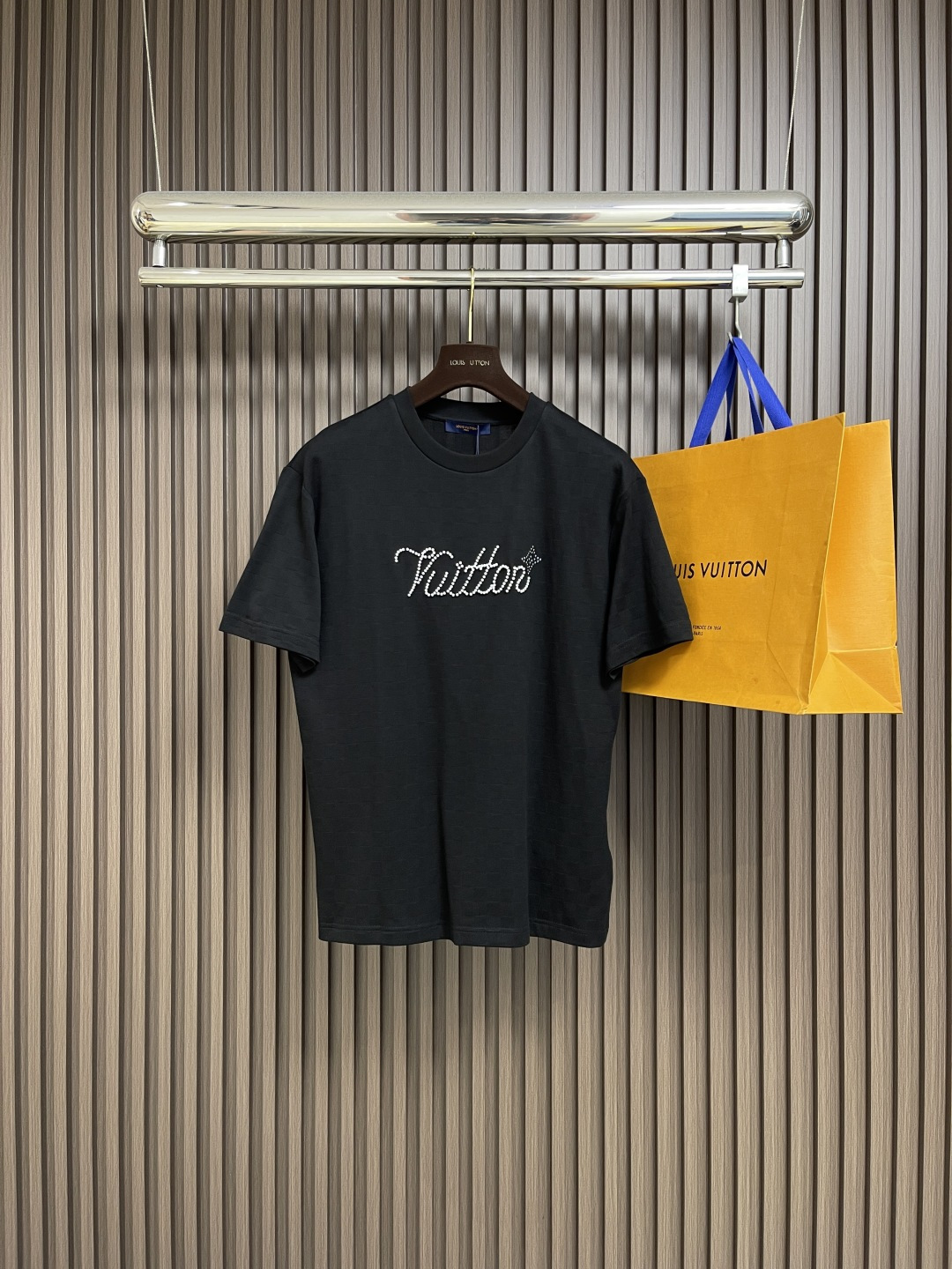 NO:523630,LV chessboard jacquard handwritten signature beaded beaded short-sleeved T-shirt, this beaded floor cotton presents a delicate texture with Der jacquard, and then beads on the chest with bright beads outlined handwritten Vuitton logo and  Flower pattern. Leather patches are placed behind. The surface of the beaded floor cloth is porous and has a similar shape to a honeycomb, which makes it more breathable and washable than ordinary knitted cloth. It not only has an elegant texture and luster, but also has a soft, smooth and textured feel. This special feel gives the fabric a high-quality touch, making the product more high-end. Combining resin beads with logo elements can create a suit that is both practical and artistic. The resin has the advantages of strong plasticity, high hardness, and good transparency; it makes this suit not only have a beautiful appearance, but also has certain practicality and personalization characteristics. Before the rivet printing begins, design the required printing patterns according to the pattern, and ensure that the pattern is simple and clear, and the number of particles is reduced. At the same time, consider the arrangement and fixing of the rivets to ensure its firmness and aesthetics. Size XS-L,,louis  vuitton, T-shirt,tees,t-shirt,alexander wang19860909LV 棋盘格提花手写签名串珠柳丁短袖T恤,本款珠地棉以Der提花呈现细腻肌理,再以莹亮串珠于胸前勾勒手写体 Vuitton标识和 Flower图案.皮革贴饰栖身背后.珠地布的表面是疏孔状的,形状与蜂巢相似,这使得它比普通针织布更透气耐洗.它不仅具有高雅的质感和光泽感,而且手感柔软、光滑、有质感,这种特殊的手感赋予了面料高品质的触感,使得产品更具高端感.将树脂珠饰与标识元素相结合,可以创造出既实用又具有艺术价值的装.树脂具有可塑性强、硬度高、透明度好等优点；使得这种装不仅具有美观的外观,还具有一定的实用性和个性化特点.铆钉印花开始制作前,根据版型设计好所需的印花图案,并确保图案简洁、明了,颗粒数还原.同时考虑铆钉的排列和固定方式,以确保其牢固性和美观性.尺码XS-L,,louis vuitton,T-shirt,tees，t-shirt,alexander wang,Men's clothing