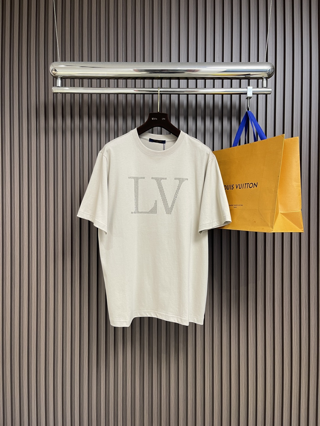 NO:600141,LV 2025SS early autumn new short-sleeved T-shirt with rhinestone letters. When the classic logo meets bright rhinestones, this V short-sleeve will unlock a new paradigm of luxury for you.  The oversized LV letters on the chest are made of countless exquisite rhinestones. They reflect sparkling luster under the light, which not only enhances the brand recognition, but also allows you to stand out in the crowd and easily become the visual center. 99% cotton blended fabric, soft and skin-friendly and drapey, comfortable and casual for daily wear; delicate stitching technology and elegant tailoring, from shoulder line to hem,  Every detail shows the luxury craftsmanship, and the texture is visible to the naked eye. The simple beige color is suitable for various dressing scenes. It can be paired with jeans to create a casual and trendy style, or it can be mixed with a suit to create a high-end look. The oversized version is friendly to the body shape. Whether you are going out on the street or socializing in luxury, it can help you interpret a unique fashion attitude. Sizes XS-L, Louis  vuitton,versace,T-shirt,tees，t-shirt,business suit,alexander wang19860909LV 2025SS早秋新款水钻字母短袖T恤,当经典标识邂逅璀璨水钻,这款V短袖为你解锁奢潮新范式. 胸前超大尺寸的LV字母,由无数颗精致水钻密镶而成,在光线下折射出粼粼光泽,将品牌辨识度拉满的同时,让你在人群中自带,轻松成为视觉中心.99％棉混纺面料,柔软亲肤且兼具垂坠感,日常穿着舒适随性；细腻的缝线工艺与考究的剪裁,从肩线到衣摆,每一处细节都彰显奢品匠心,质感肉眼可见.简约米色调适配各种穿搭场景,可搭配牛仔打造随性潮范,也能与西装混搭出高级感,oversize版型对身形友好,无论是街头出街还是轻奢社交,都能助你演绎独树一帜的时尚态度.尺码XS-L,,louis vuitton,versace,T-shirt,tees，t-shirt,business suit,alexander wang,Men's clothing