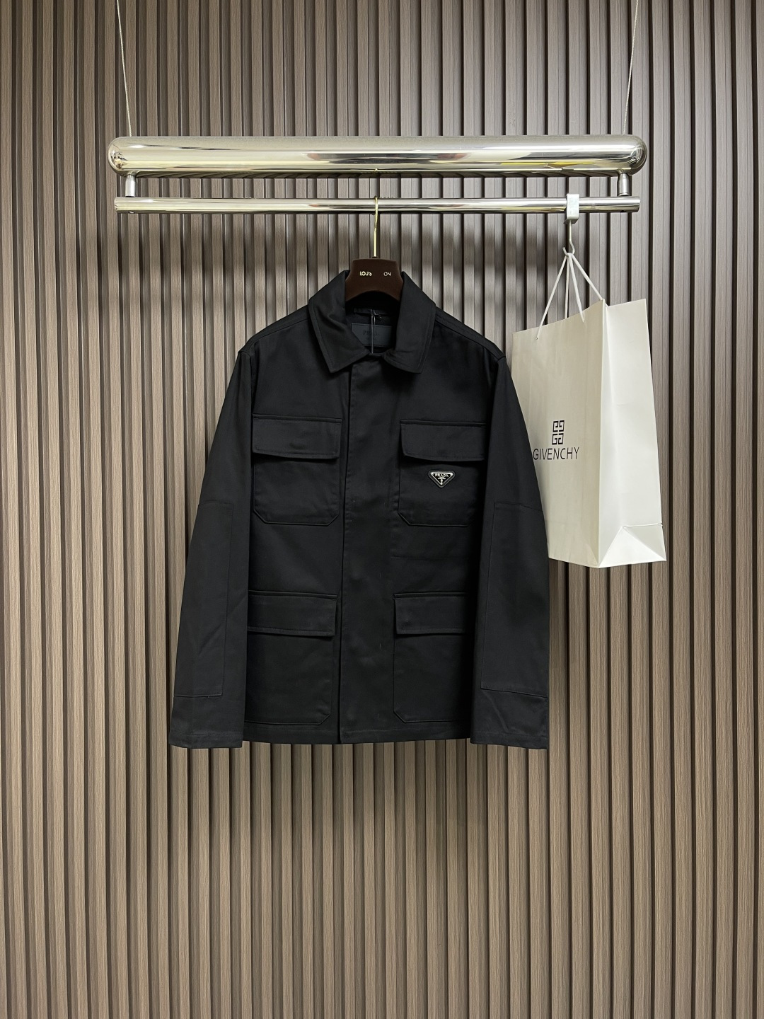 NO:537628,PRADA  The cotton workwear style jacket uses 45° oblique warp and weft to construct the fabric muscles and bones. The tightly arranged cotton yarns form a natural three-dimensional texture, giving them a practical base that is anti-wrinkle and wear-resistant. At the same time, the matte texture echoes the rough aesthetics of the workwear style. It retains the natural skin-friendly and sweat-absorbing ability of the cotton fibers, while taking into account both warmth and breathability. The natural stiffness of the fabric is used to reinforce the shoulder joints through double-layer cotton yarn to create a sculptural wide shoulder profile to avoid soft collapse and deformation. The cuffs are embedded with invisible thread lining to ensure freedom in every move. Through low-temperature ironing and oblique  The natural hardness of the pattern fabric is integrated to create a 30-degree bracing angle, so that the neckline fits the neck curve and improves wear comfort. Abandon traditional lining, shape the silhouette with the crispness of the fabric itself, reducing redundant layers while improving breathability. The hidden button closure and flat bottom edge design enhance the tough temperament and loose fit to avoid bloating. The symmetrical flip patch pocket enhances practicality, and the three-dimensional silhouette adds a sense of layering. The tight stitching at the edges makes the bag solid while adding beauty. Size S-XL, prada, jackets  & coats,alexander wang19860909PRADA 棉质工装风夹克,以45°斜向经纬交织构筑面料筋骨,紧密排列的棉纱形成天然立体肌理,赋予抗皱耐磨的实用基底,同时通过哑光质感呼应工装风的粗粝美学,其保留了棉纤维天然的亲肤性和吸汗能力,同时又兼顾保暖性和透气性.利用面料天然硬挺性,通过双层棉纱加固肩线接缝,打造雕塑感宽肩轮廓,避免软塌变形.袖口内嵌隐形螺纹衬条,确保举手投足间的自如.通过低温压烫与斜纹布自然的硬度融合,打造30度力挺角度,使领口贴合颈部曲线,提升穿着舒适度.摒弃传统衬里,以面料本身的挺括度塑造廓形,减少冗余层次的同时提升透气性.隐藏式纽扣开合和平直底边设计强化硬朗气质与宽松版型形成平衡,避免臃肿感.对称翻盖贴袋强化实用性,立体廓形增添层次感.边缘处紧密的缝线使袋体牢固的同时又增添美感.尺码S-XL,,prada,jackets & coats,alexander wang,Men's clothing