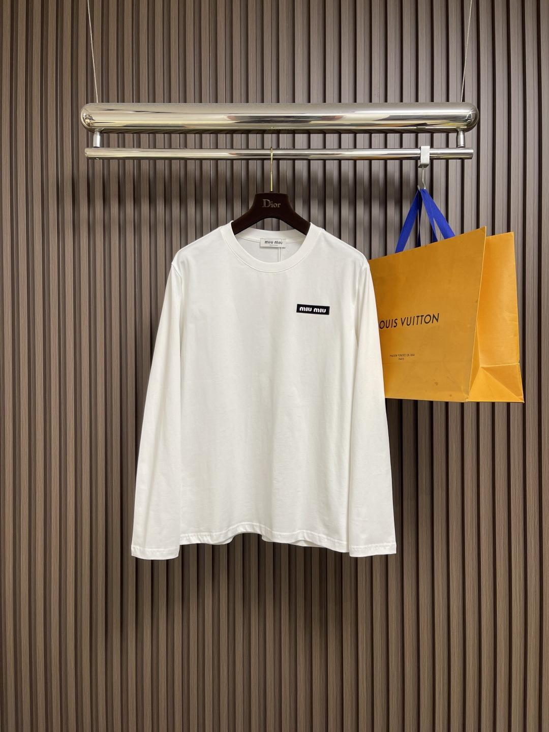 NO:529343,MIUMIU 2025SS round neck long-sleeved T-shirt, using high-grade 24 combed cotton yarns, ensuring color uniformity through the 'dyeing first and then weaving' process. The yarn is twisted by double strands to improve pill resistance, and the finish of the cloth is better than that of ordinary cotton fabrics. The 190g weight of the version is precisely controlled by 18-needle fine needle-drawing round machine, taking into account the drape and clarity. It is necessary to cooperate with a constant temperature and humidity workshop to avoid yarn tension fluctuations. Tight spinning structure. Learn from Swiss Rider tight spinning technology, the yarn hair is reduced by 60, and the fabric density reaches 156-needle inches 2, achieving the touch of the baby's skin while maintaining an elastic recovery rate of more than 8%. Size S-3XL Size bust 100 Shoulder width 44 Sleeves 68 Sleeves 62 M Size bust 104 Shoulder width 45.5 Sleeves 70 Sleeves 63 L Size bust 108  Shoulder width 47 Clothes length 72 Sleeve length 64 XL size Bust 112 Shoulder width 48.5 Clothes length 74 Sleeve length 65 2XL size Bust 116 Shoulder width 50 Clothes length 76 Sleeve length 66 3XL size Bust 120 Shoulder width 51.5 Clothes length 78 Sleeve length 67,,miumiu,tees,t-shirt,alexander wang19860909MIUMIU 2025SS圆领长袖T恤,采用高品级24支精梳棉纱线,通过「先染后织」工艺确保色彩均匀性,纱线经双股加捻提升抗起球性,布面光洁度优于普通棉织物.对版190克重精密调控通过18针细针距圆机编织,兼顾垂坠感与挺括性,需配合恒温恒湿车间避免纱线张力波动.紧密纺结构 借鉴瑞士立达紧密纺技术,纱线毛羽减少60,织物密度达156针英寸2,实现婴儿肌肤触感的同时保持8％以上的弹性回复率.尺码S-3XL S码胸围100 肩宽44 衣长68袖长62 M码胸围104 肩宽45.5 衣长70袖长63 L码 胸围108 肩宽47 衣长72 袖长64 XL码 胸围112 肩宽48.5衣长74袖长65 2XL码 胸围116 肩宽50 衣长76袖长66 3XL码 胸围120 肩宽51.5衣长78袖长67,,miumiu,tees，t-shirt,alexander wang,Men's clothing