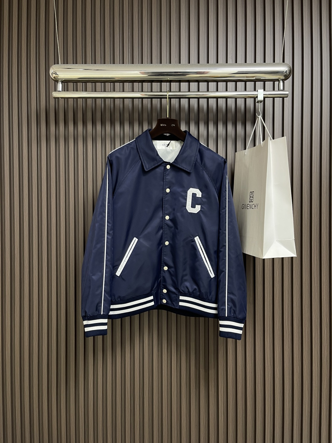 NO:540679,Celine  2025FW early autumn new college-style baseball uniform, the giant white 'C' letter embroidery on the front chest and the three-dimensional embroidery on the back, are created with exclusive brand craftsmanship, with precise stitching and three-dimensional sense. Against the backdrop of the navy blue satin nylon fabric, it not only releases the vitality and tension of the American Academy, but also highlights the exquisite style of the French luxury brand; the metal engraving quad buckles are clear brand letter logos conveying the brand texture from the opening and closing; the contrasting stripes ribs on the hem and cuffs are classic elements of the college style, and at the same time, the crisp style of the clothes is strengthened, allowing the retro trend to be filled with details. The blue satin nylon fabric is made of silky touch and crisp draping, which is not easy to wrinkle and easy to handle in daily wear.  ; The fine edge locking and sewing craftsmanship inside continues the brand's strict quality requirements, making this baseball uniform not only a piece of clothing, but also a fashionable artwork that can be collected for a long time. The loose style of the same style of men and women is suitable for a variety of figures and styles. It can be paired with a white T-shirt inside to create a street style; it can also be layered with a pleated skirt to interpret the sweet and cool feeling of the college; even with suit pants, it can collide with a unique accent of 'elegant luxury'. From campus commuting to urban outings, to light luxury socializing, it uses the attribute of 'unbounded style' to help you become a fashion protagonist with a retro and high-end feel in every occasion. Size S-XL, celine, skirts, business  suit,alexander wang19860909Celine 2025FW早秋新品学院风棒球服,前胸的巨型白色'C'字母刺绣与后背的品牌字母立体绣花,采用品牌独家工艺打造,针脚精密且富有立体感,在藏蓝色缎面锦纶面料的衬托下,既释放美式学院的活力张力,又彰显法式奢牌的精致格调；金属刻字四合扣上清晰的品牌字母标识,从开合间传递品牌质感；下摆与袖口的撞色条纹罗纹,学院风经典元素,同时强化衣物的挺括版型,让复古潮范在细节处拉满.选用蓝色缎面锦纶面料,兼具丝滑触感与挺括垂坠感,日常穿着不易起皱且便于打理；内里的精细锁边与车缝工艺,延续品牌对品质的严苛要求,让这件棒球服不仅是穿搭单品,更是可长久收藏的时尚艺术品.男女同款的宽松版型,适配多元身形与风格.可内搭白T配,打造街头潮酷风；也能叠穿配百褶裙,演绎学院甜飒感；甚至搭配西装裤,都能碰撞出'雅痞奢潮'的独特腔调.从校园通勤到都市出街,再到轻奢社交,它以'风格无界'的属性,助你在每一个场合都成为兼具复古感与高级感的时尚主角.尺码S-XL,,celine,skirts,business suit,alexander wang,Men's clothing