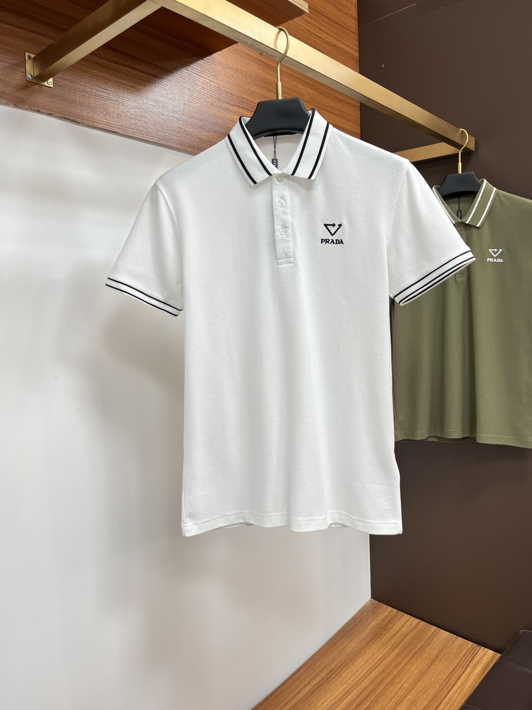 NO:519600,Prada 2025 spring and summer classic Polo collar design, paired with simple single-breasted lines, neat and smooth lines, cleverly modifying the neck lines, showing elegant and gentlemanly style. The exquisite brand logo on the left chest adopts traceless pressing process, delicate and flat, low-key, and luxurious texture, showing the brand's ingenuity and quality pursuit in the subtleties. Selected high-quality fabrics, soft and smooth touch, good breathability, and comfortable and comfortable to wear. Whether it is to wear casual trousers to show professionalism and ability; or to combine it with jeans to create a daily look to create a relaxed and comfortable atmosphere, it can be perfectly adapted. AX helps you interpret diverse styles with a calm attitude and show your unique taste. Size M-3XL,,prada,jeans,alexander wang19860909普拉达 2025春夏经典的Polo领设计,搭配简洁的单排扣,线条利落流畅,巧妙修饰颈部线条,彰显优雅绅士格调.左胸处精致的品牌标识,采用无痕压胶工艺,细腻而平整,低调间流露奢华质感,于细微之处展现品牌匠心与品质追求. 精选优质面料,触感柔软顺滑,透气性佳,穿着舒适自在.无论是搭配休闲西裤出席商务场合,展现专业干练；还是与牛仔裤组合打造日常造型,营造轻松惬意氛围,它都能完美适配,AX助你以从容姿态诠释多样风格,尽显独特品味. 尺码M-3XL,,prada,jeans,alexander wang,Men's clothing