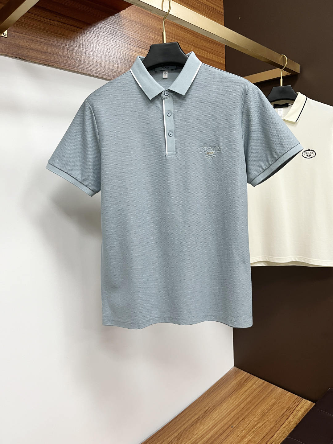 NO:522062,Prada 2025 spring and summer classic Polo collar design, paired with simple single-breasted lines, neat and smooth lines, cleverly modifying the neck lines, showing elegant and gentlemanly style. The exquisite brand logo on the left chest adopts traceless pressing process, delicate and flat, low-key, and luxurious texture, showing the brand's ingenuity and quality pursuit in the subtleties. Selected high-quality fabrics, soft and smooth, breathable, and comfortable and comfortable to wear. Whether it is to wear casual trousers to show professionalism and ability; or to combine them with jeans to create a daily look to create a relaxed and comfortable atmosphere, it can be perfectly adapted. AM helps you interpret diverse styles with a calm attitude and show your unique taste. Size M-3XL,,prada,jeans,alexander wang19860909普拉达 2025春夏经典的Polo领设计,搭配简洁的单排扣,线条利落流畅,巧妙修饰颈部线条,彰显优雅绅士格调.左胸处精致的品牌标识,采用无痕压胶工艺,细腻而平整,低调间流露奢华质感,于细微之处展现品牌匠心与品质追求. 精选优质面料,触感柔软顺滑,透气性佳,穿着舒适自在.无论是搭配休闲西裤出席商务场合,展现专业干练；还是与牛仔裤组合打造日常造型,营造轻松惬意氛围,它都能完美适配,AM助你以从容姿态诠释多样风格,尽显独特品味. 尺码M-3XL,,prada,jeans,alexander wang,Men's clothing