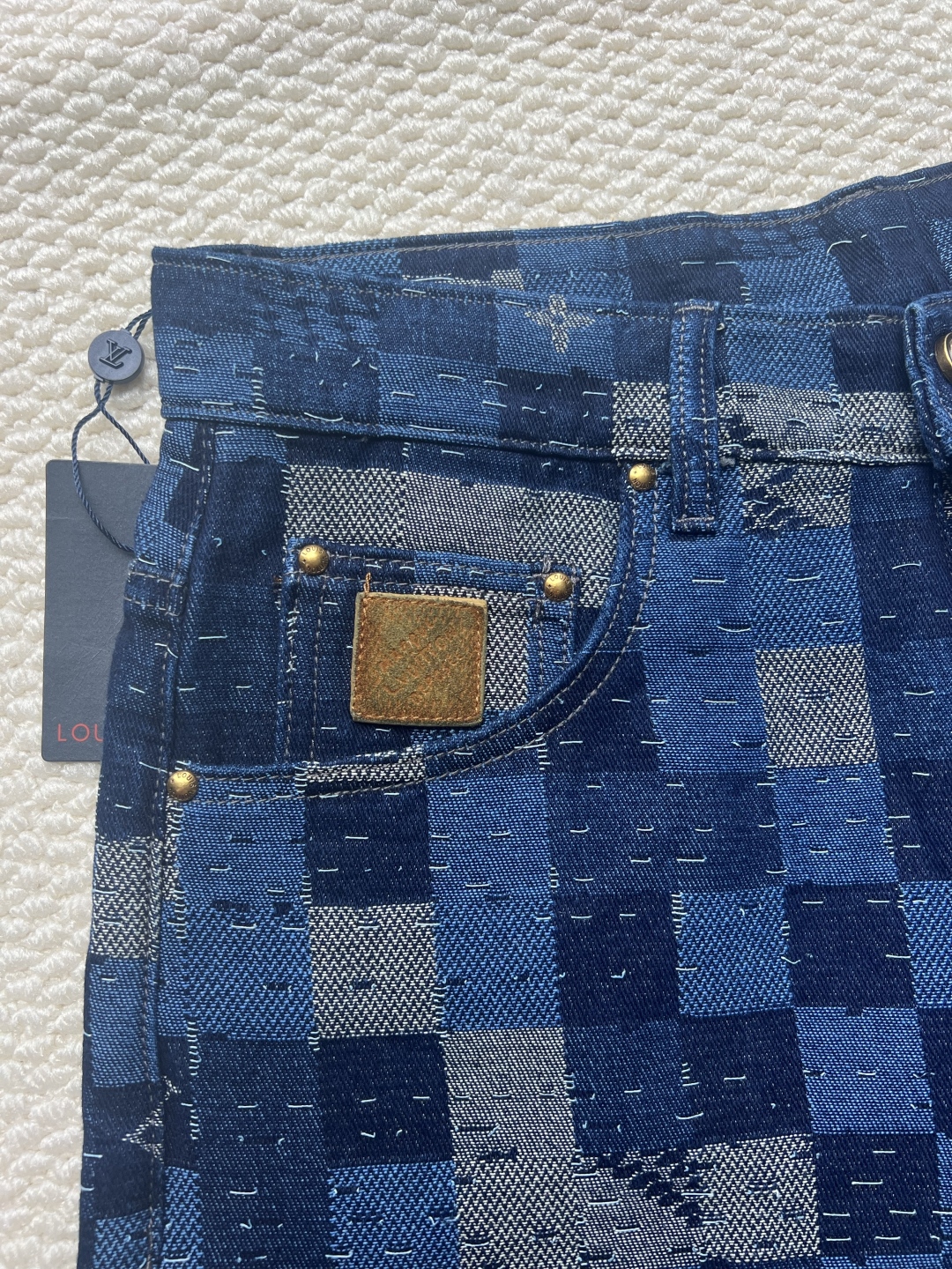 P240 LOUIS VUITTON✖️Nigo联名提花棋盘格牛仔长裤
工艺说明:这款滑板来自Pharrell Williams与Nigo合作的2025秋冬系列,采用100%纯棉面料打造,兼具舒适度与耐用性。设计上巧妙融合了品牌标志性的Damier格纹元素,通过独特的拼缝工艺向日本传统拼布技艺致敬。裤身采用经典五袋剪裁,搭配珠光纽扣前襟和铆钉装饰,细节处尽显精致。全幅标识提花工艺彰显品牌辨识度,正绒面革标签则增添了高级质感。整体版型专为滑板运动设计,既保持活动自由度又不失时尚感。可与同系列搭配,完整呈现秀场造型。珠光元素的运用与格纹图案相得益彰,展现出品牌对传统工艺与现代潮流的完美平衡。
码数:30-32-34-36