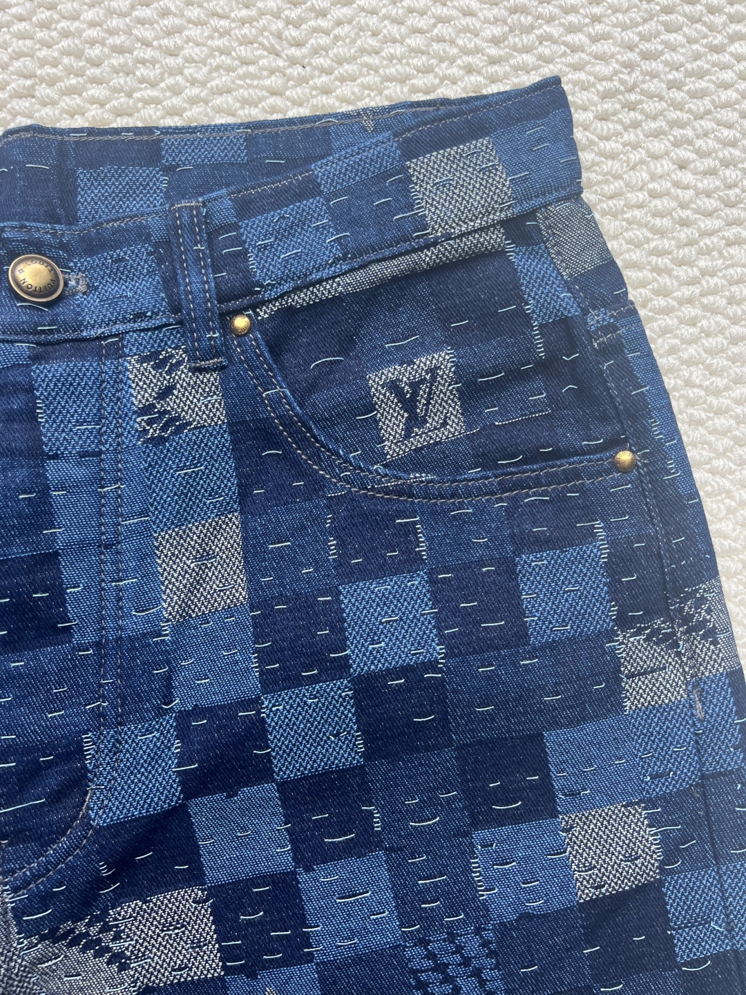P240 LOUIS VUITTON✖️Nigo联名提花棋盘格牛仔长裤
工艺说明:这款滑板来自Pharrell Williams与Nigo合作的2025秋冬系列,采用100%纯棉面料打造,兼具舒适度与耐用性。设计上巧妙融合了品牌标志性的Damier格纹元素,通过独特的拼缝工艺向日本传统拼布技艺致敬。裤身采用经典五袋剪裁,搭配珠光纽扣前襟和铆钉装饰,细节处尽显精致。全幅标识提花工艺彰显品牌辨识度,正绒面革标签则增添了高级质感。整体版型专为滑板运动设计,既保持活动自由度又不失时尚感。可与同系列搭配,完整呈现秀场造型。珠光元素的运用与格纹图案相得益彰,展现出品牌对传统工艺与现代潮流的完美平衡。
码数:30-32-34-36