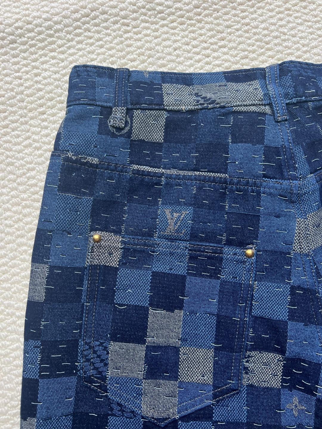 P240 LOUIS VUITTON✖️Nigo联名提花棋盘格牛仔长裤
工艺说明:这款滑板来自Pharrell Williams与Nigo合作的2025秋冬系列,采用100%纯棉面料打造,兼具舒适度与耐用性。设计上巧妙融合了品牌标志性的Damier格纹元素,通过独特的拼缝工艺向日本传统拼布技艺致敬。裤身采用经典五袋剪裁,搭配珠光纽扣前襟和铆钉装饰,细节处尽显精致。全幅标识提花工艺彰显品牌辨识度,正绒面革标签则增添了高级质感。整体版型专为滑板运动设计,既保持活动自由度又不失时尚感。可与同系列搭配,完整呈现秀场造型。珠光元素的运用与格纹图案相得益彰,展现出品牌对传统工艺与现代潮流的完美平衡。
码数:30-32-34-36